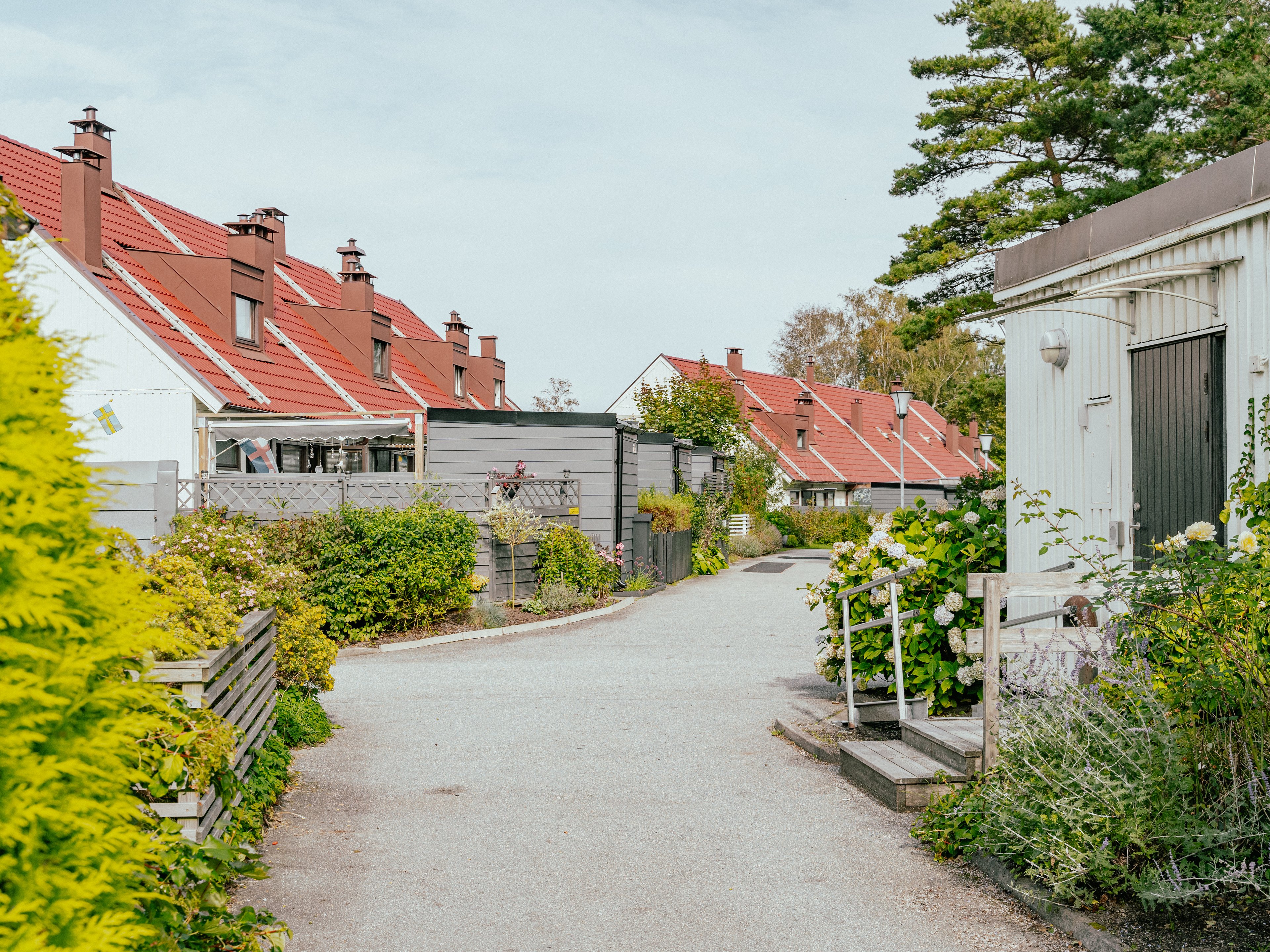 En gågata genom ett radhusområde med planteringar och uteplatser