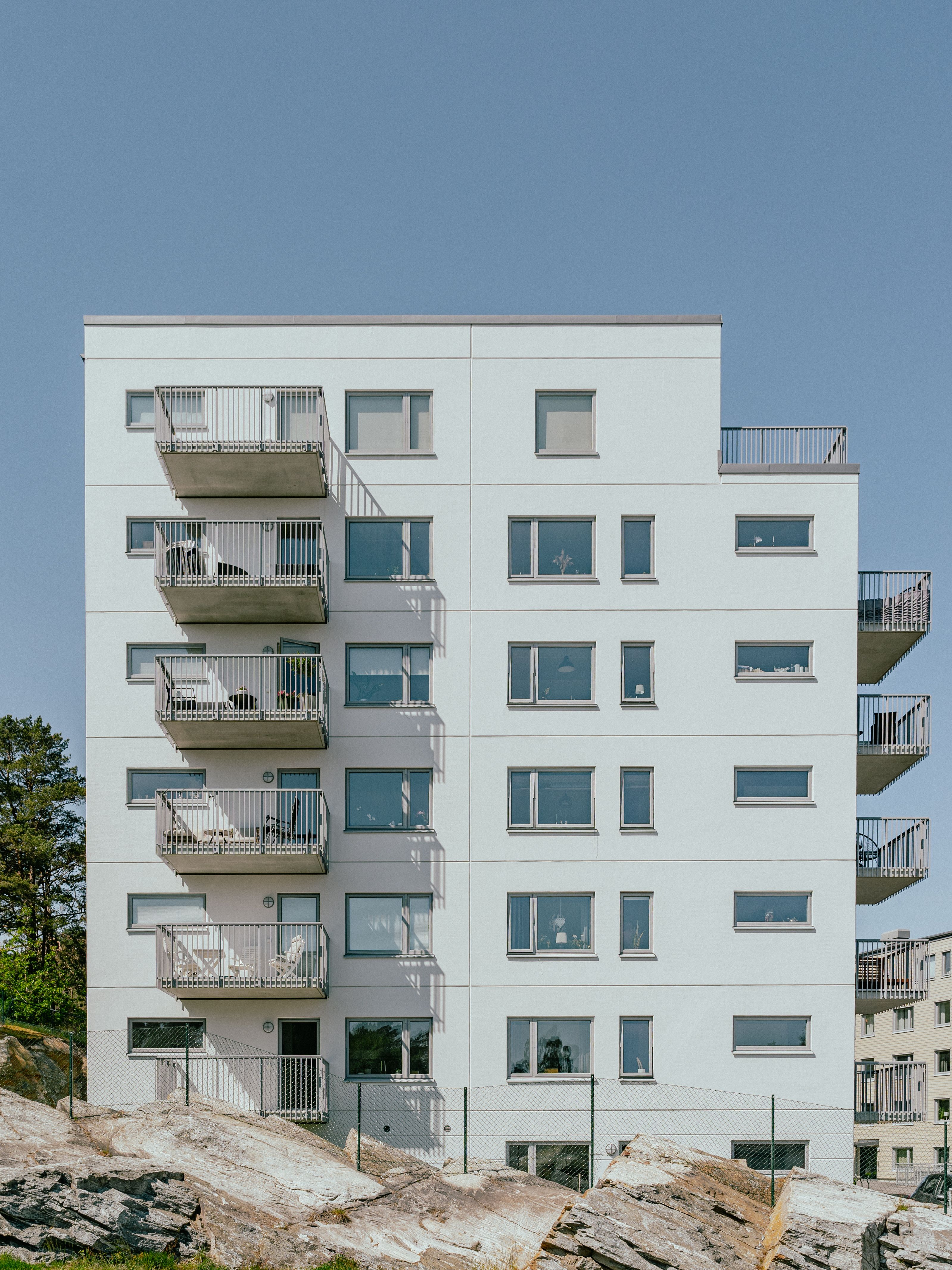 Fasaden av ett sjuvåningshus med en bergsknalle framför