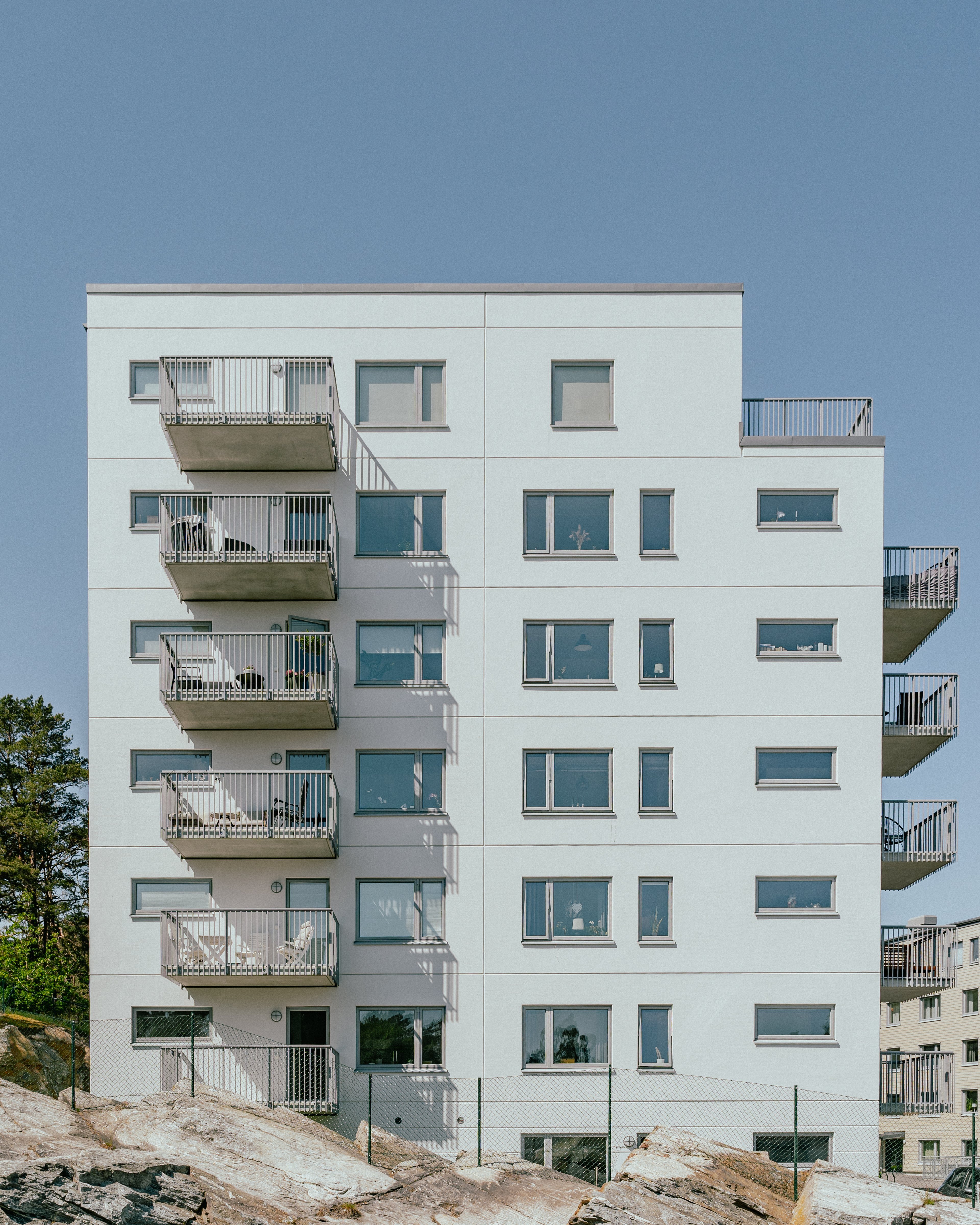 Fasaden av ett sjuvåningshus med en bergsknalle framför