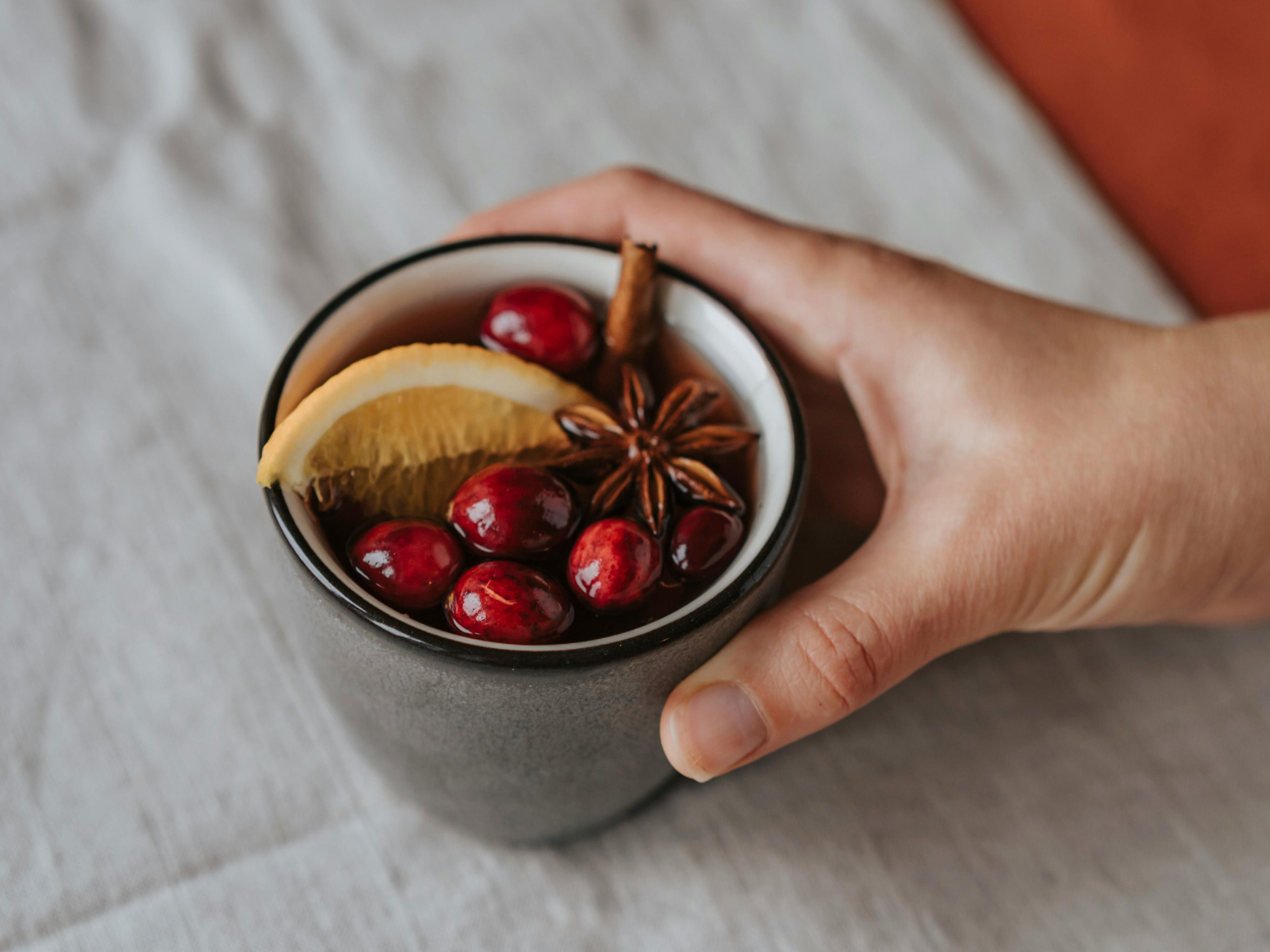 En hand håller en mugg med glögg