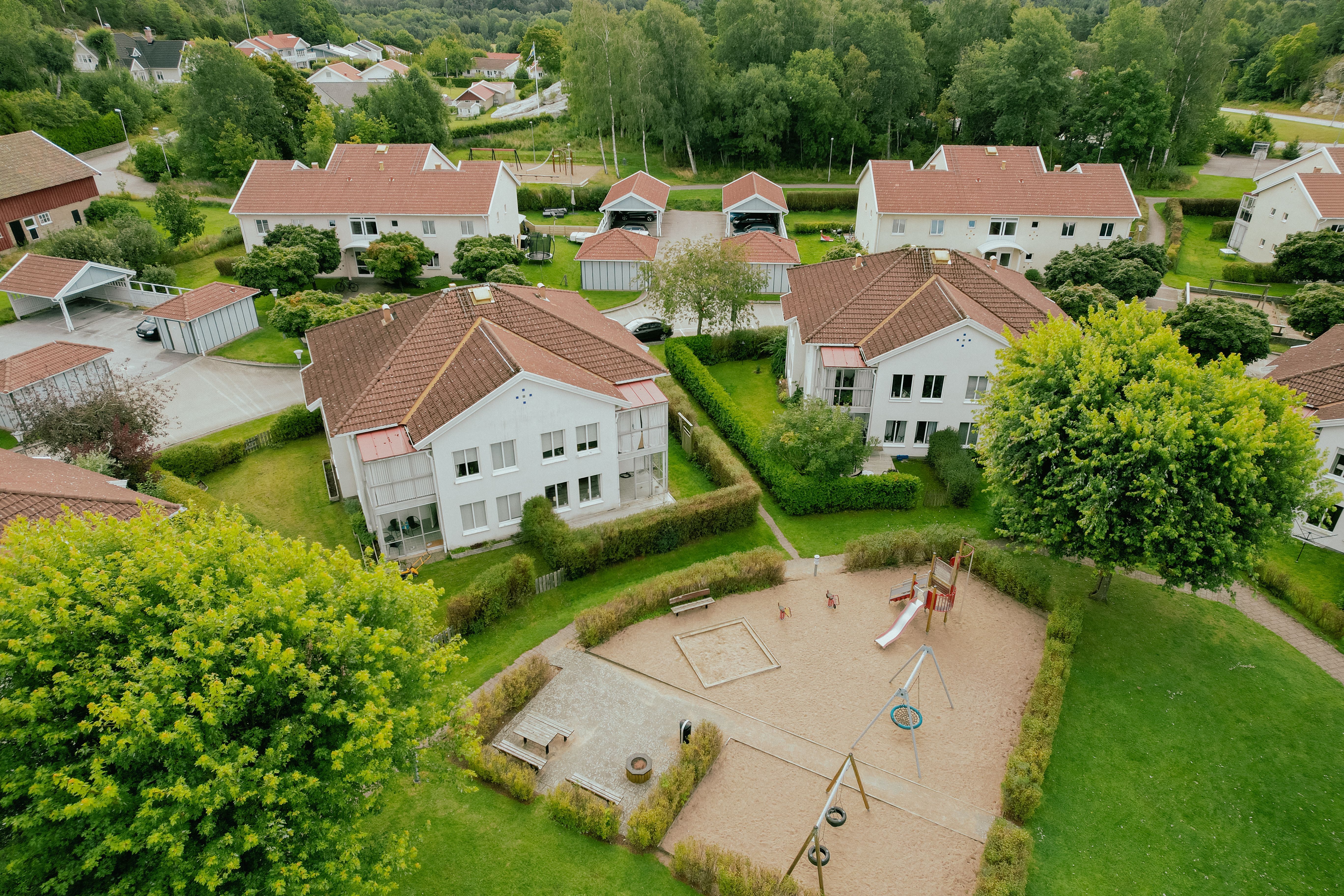 Flygbild över ett bostadsområde med lekplats och stor gräsmatta