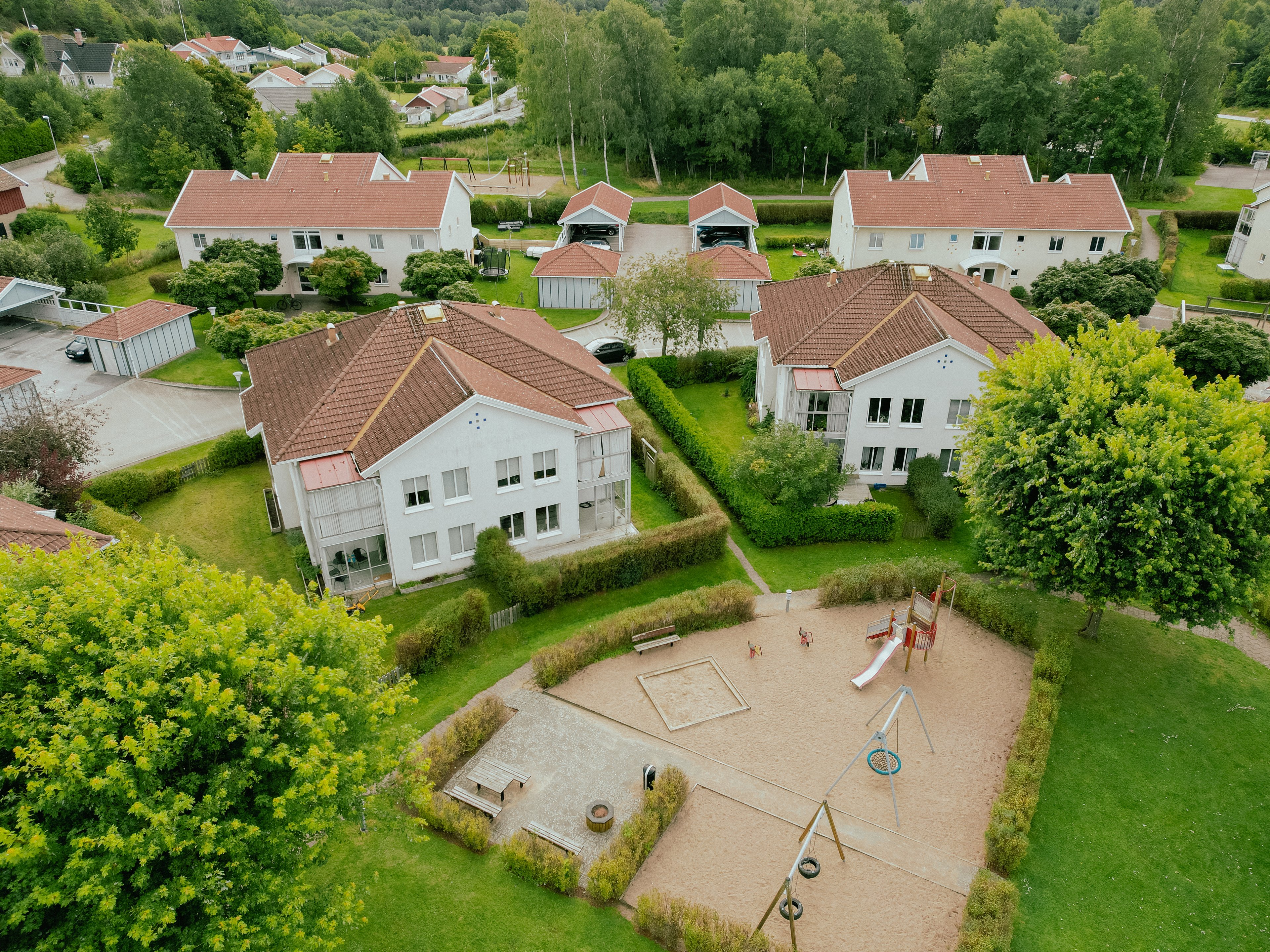 Flygbild över ett bostadsområde med lekplats och stor gräsmatta