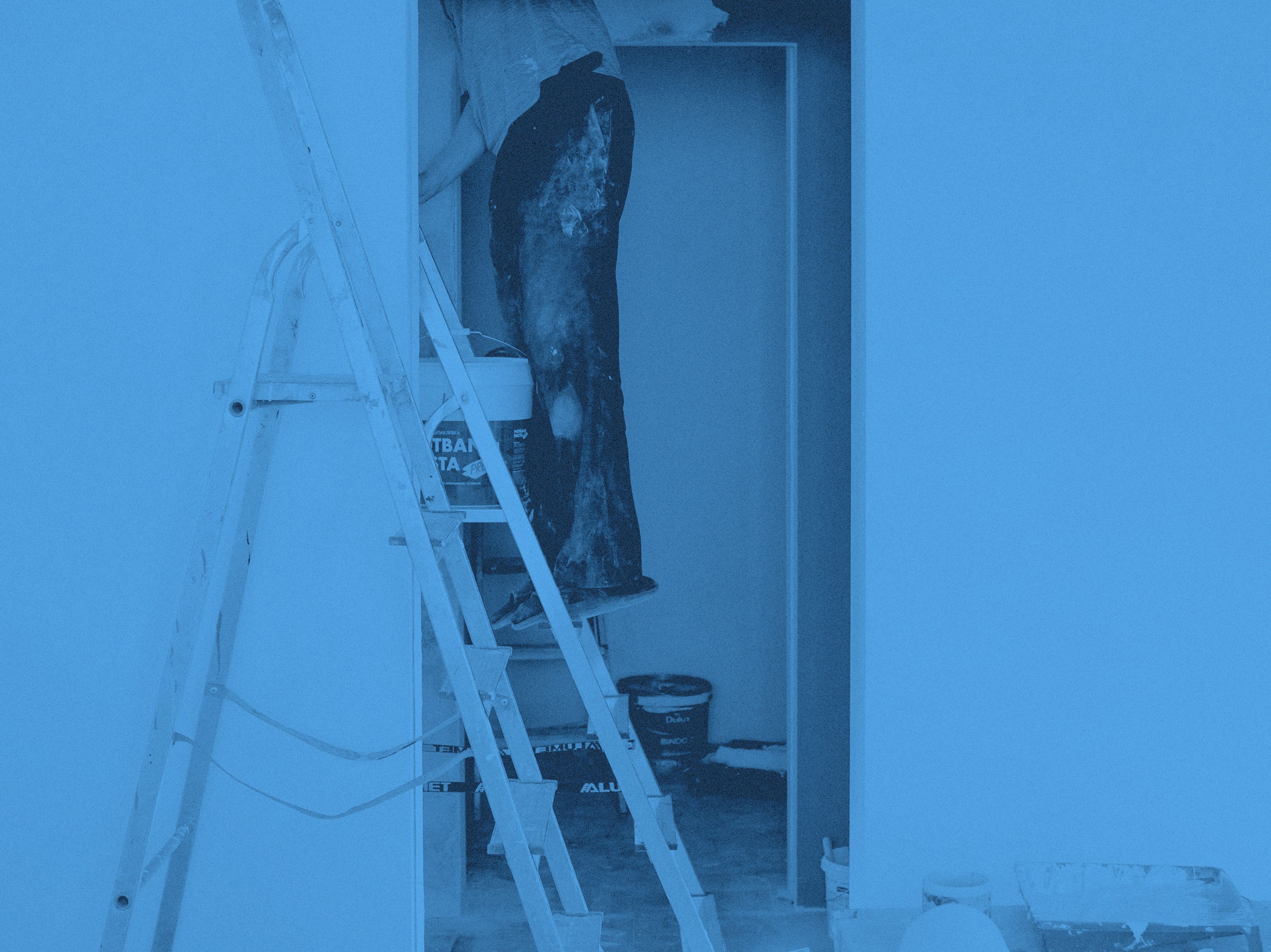 En man står på stege och målar