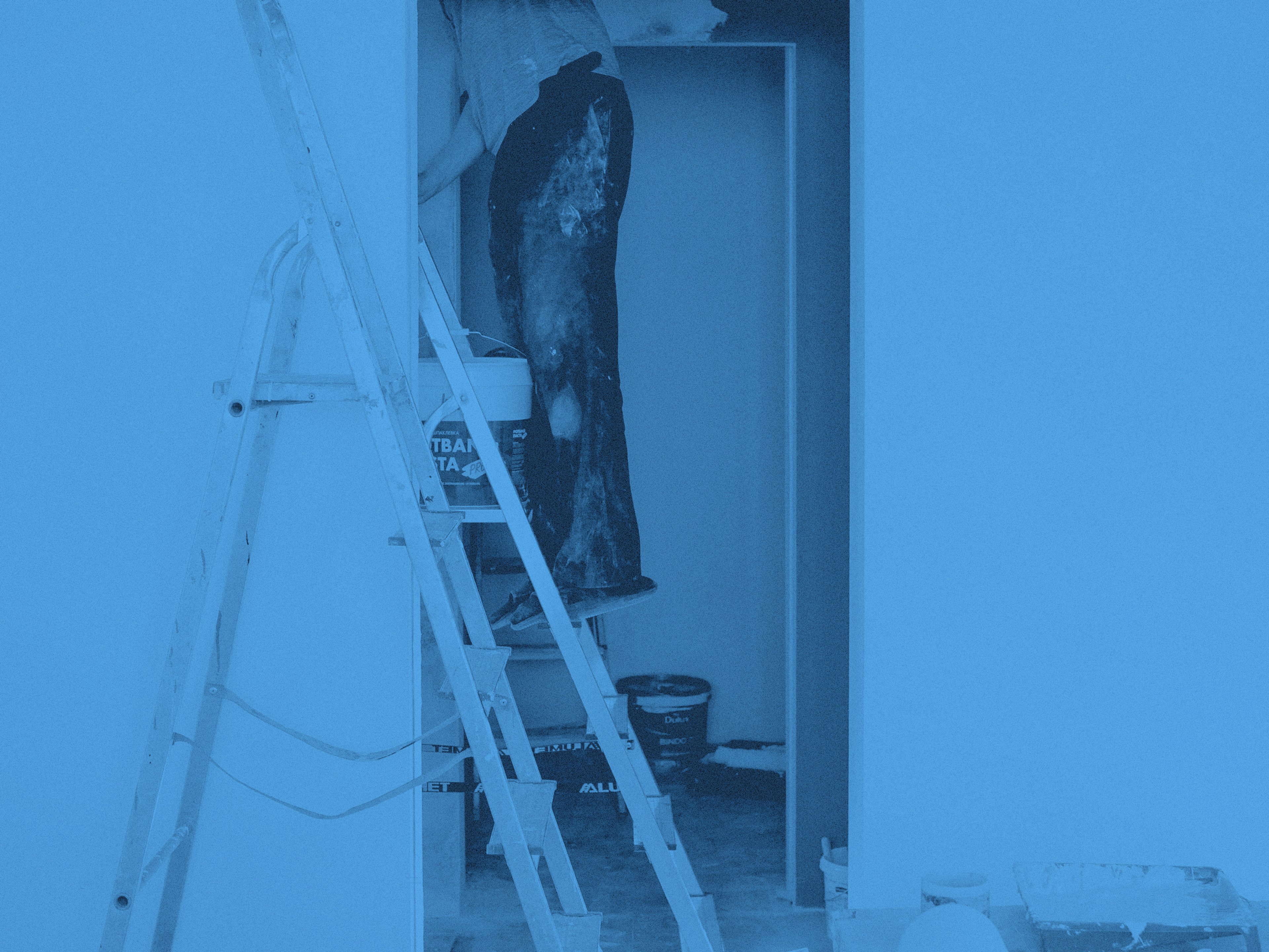 En man står på stege och målar