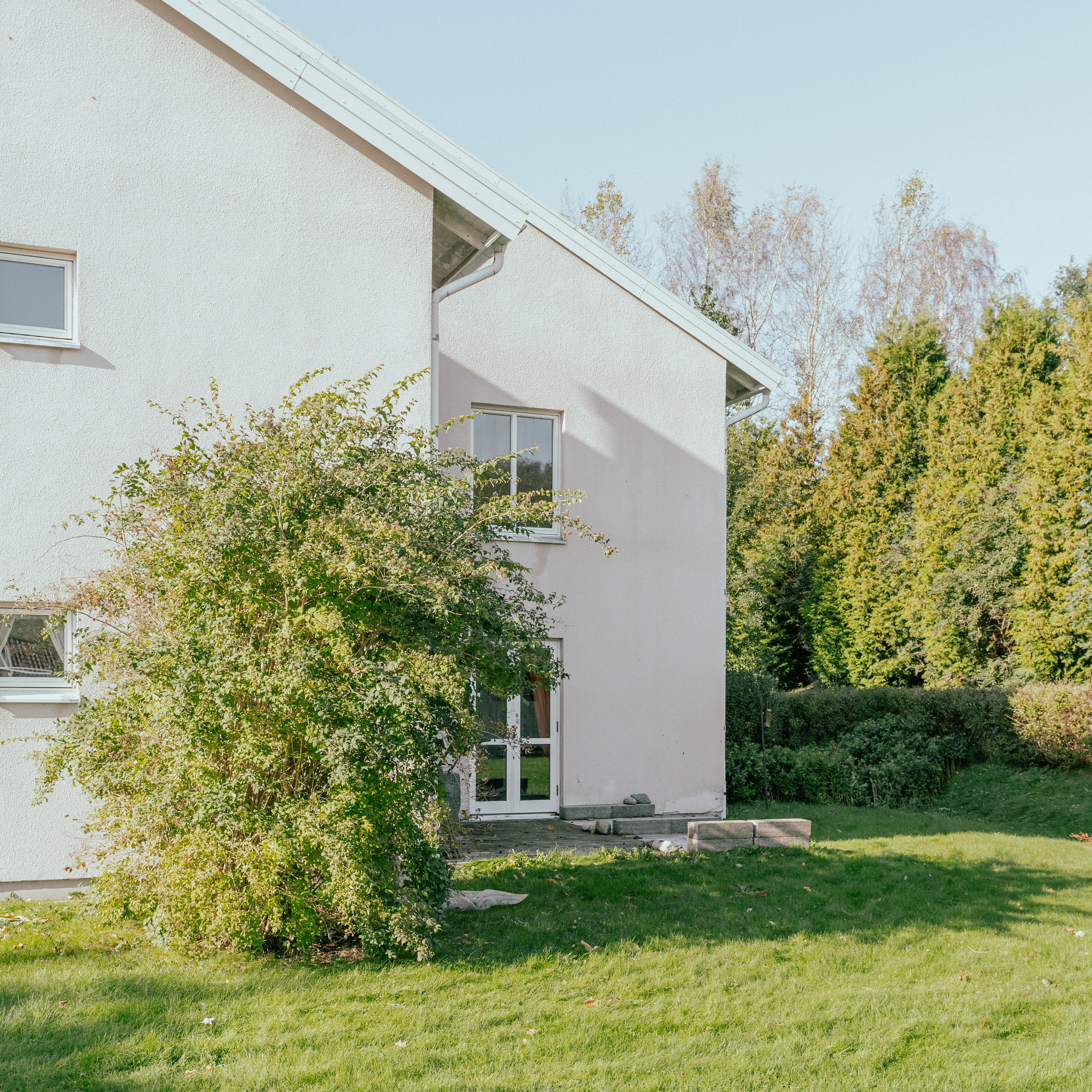 Fasad på tvåvåningshus med gräsmatta och buske