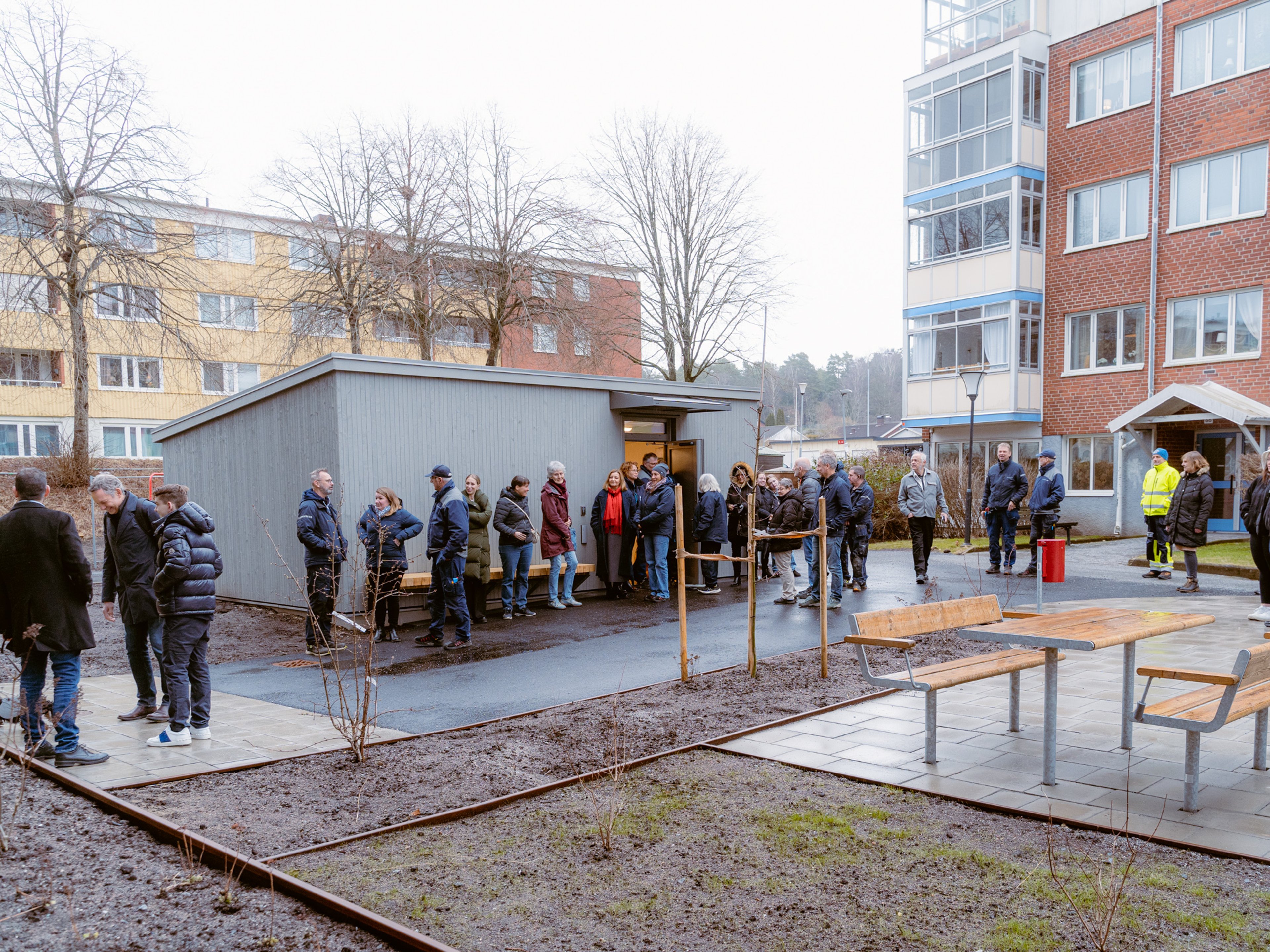 En lång kö av människor på gården mellan två hus
