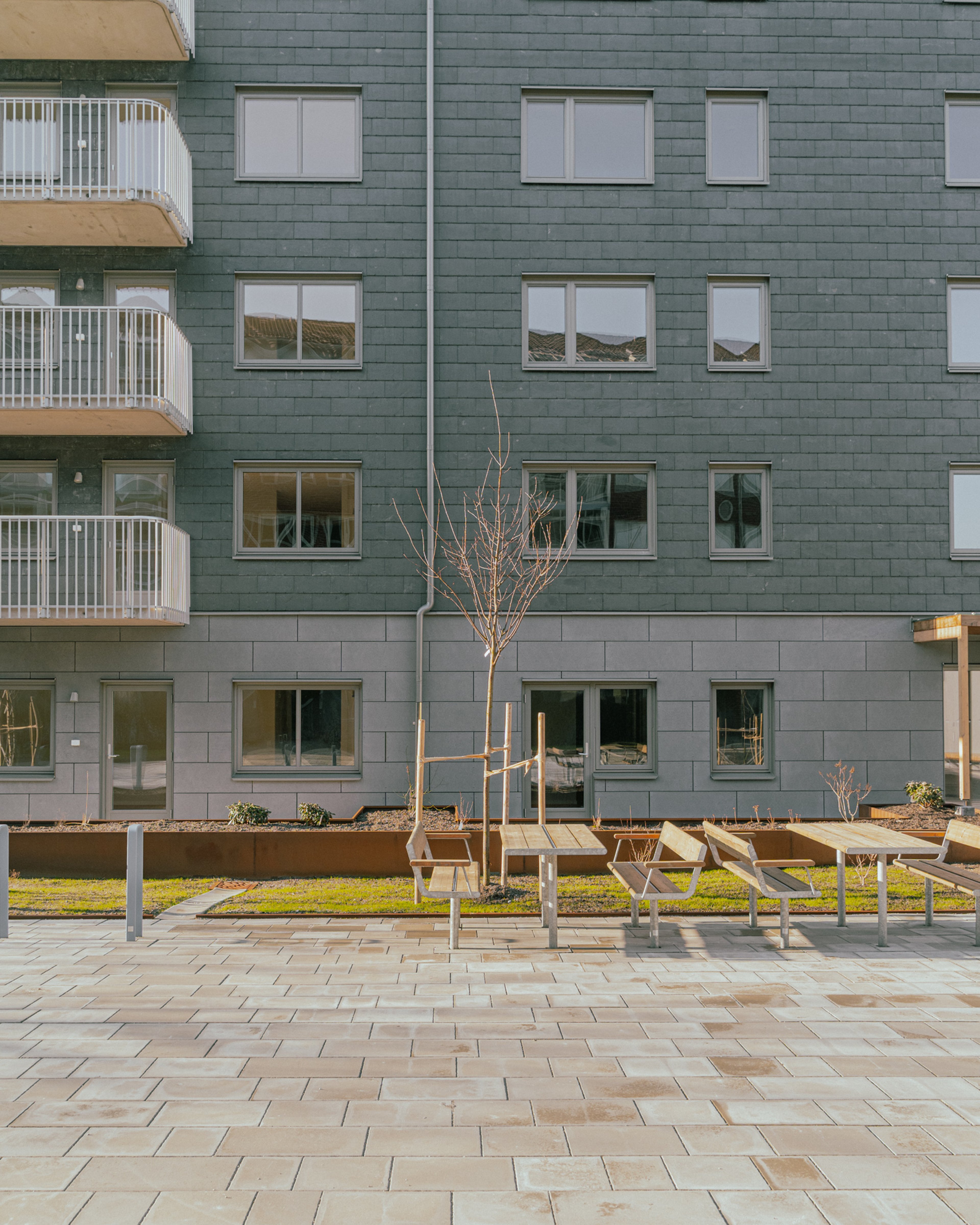 En husfasad med bänkar och bord framför