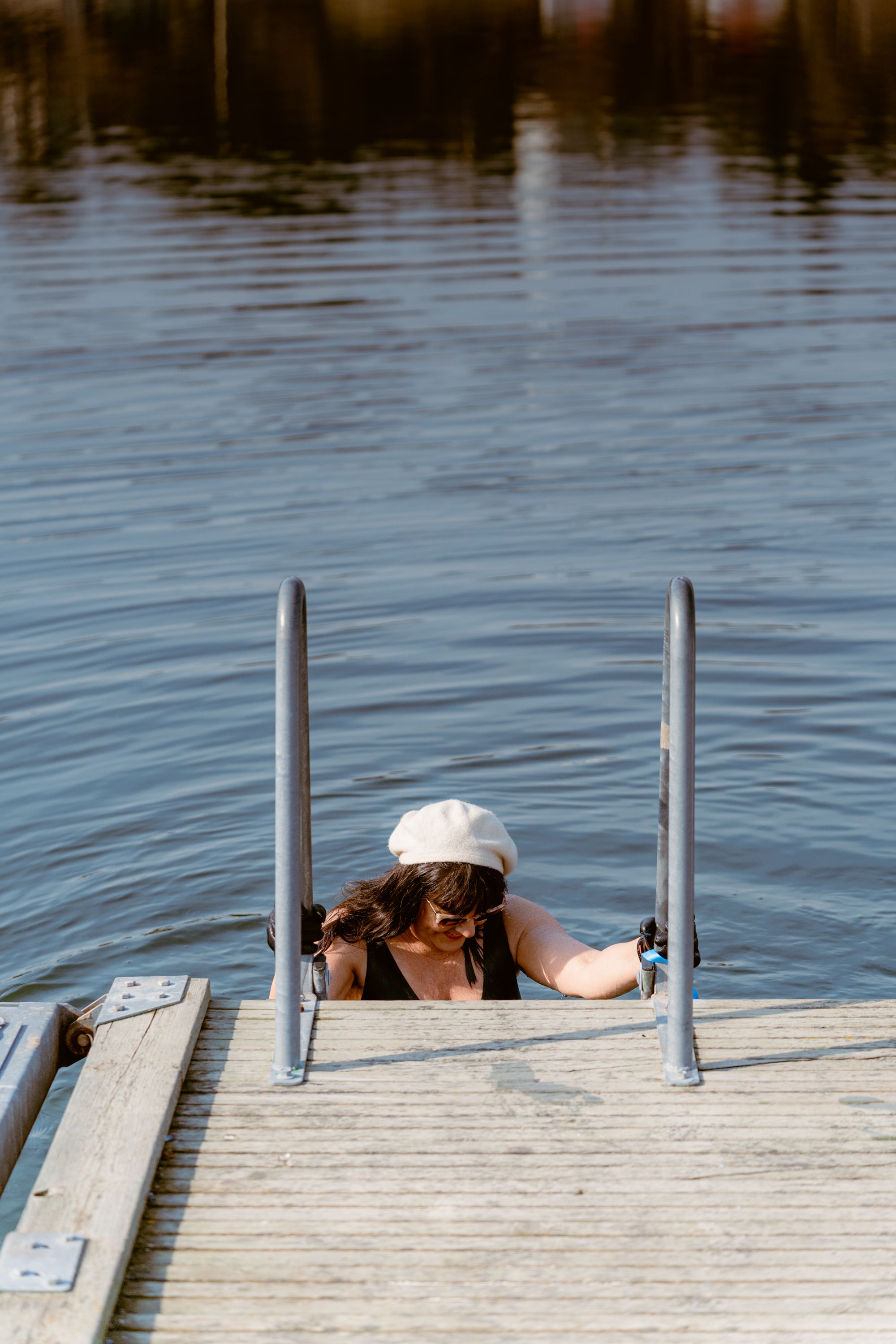 En kvinna på en badstege på väg ner i vattnet