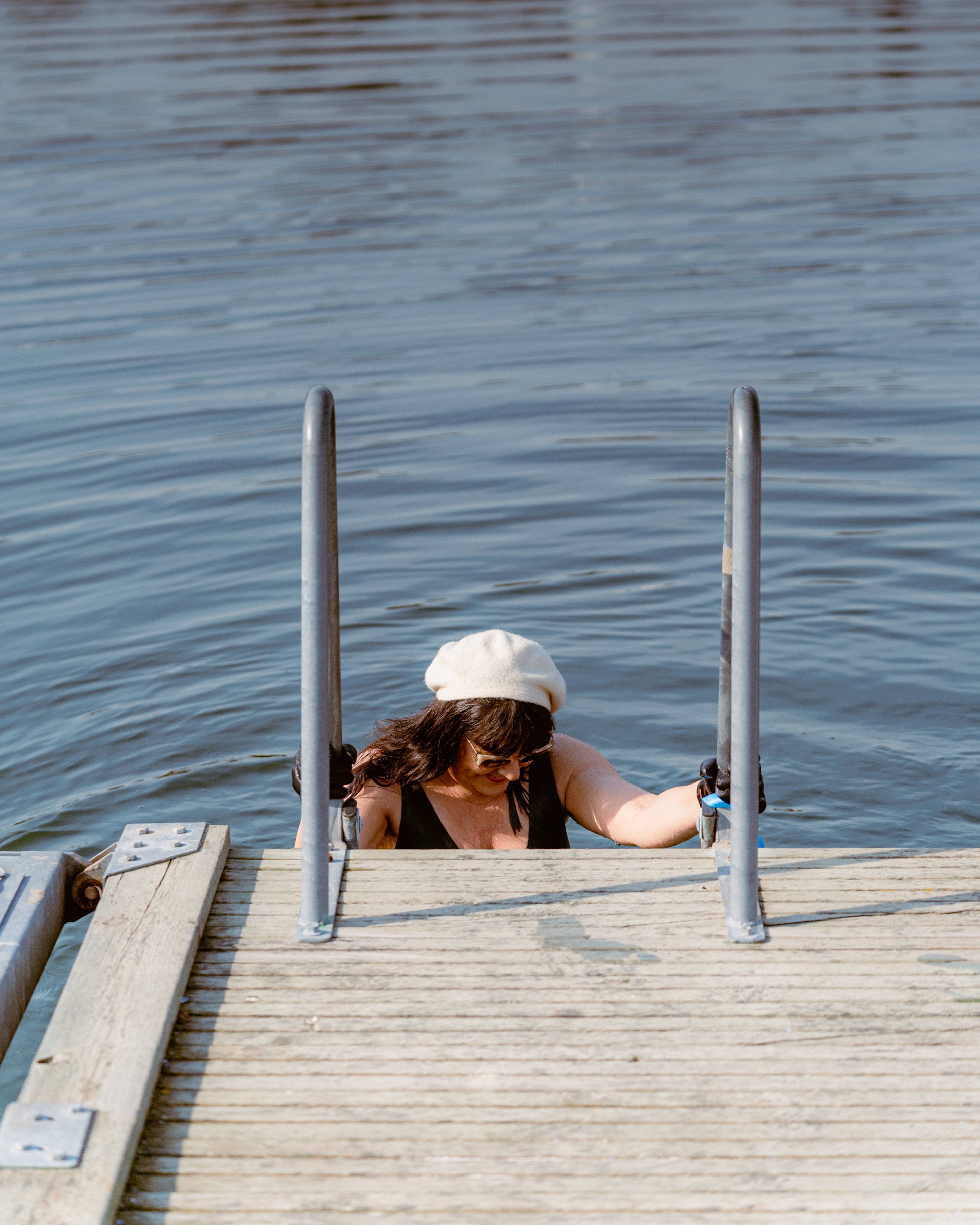En kvinna på en badstege på väg ner i vattnet
