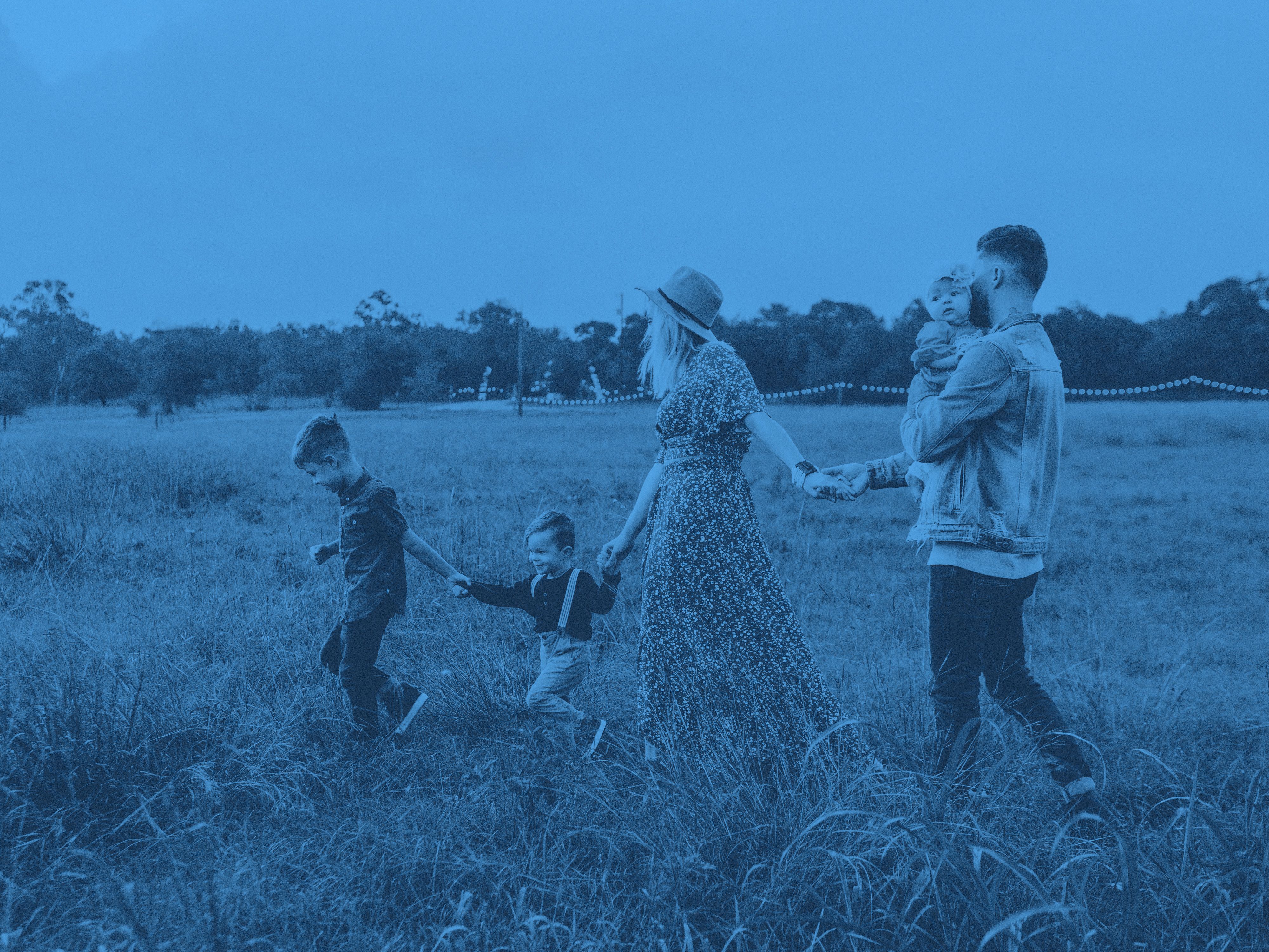 En familj på fem personer vandrar över en äng