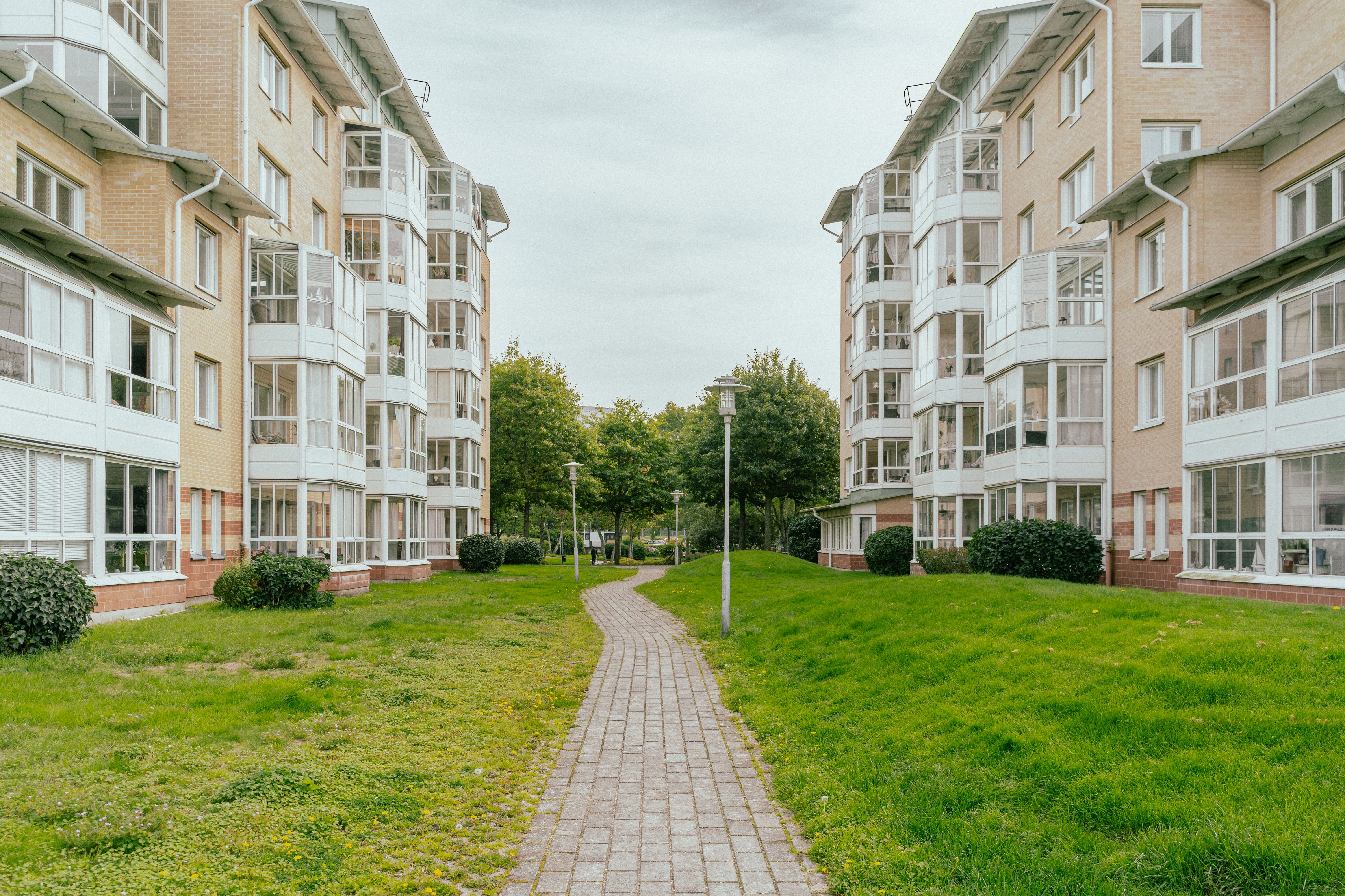 En stenlagd gång genom en stor gräsyta mellan två husfasader