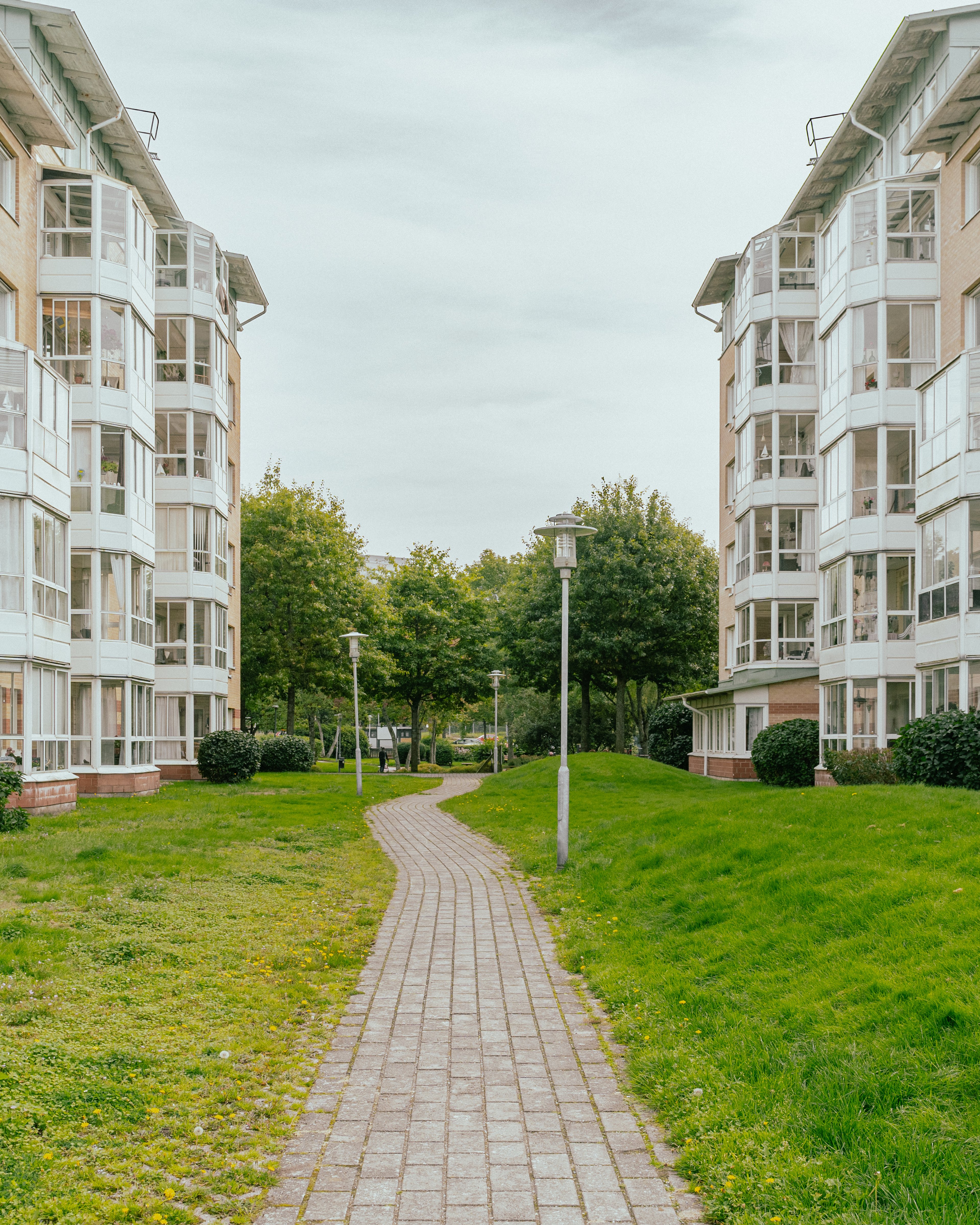 En stenlagd gång genom en stor gräsyta mellan två husfasader