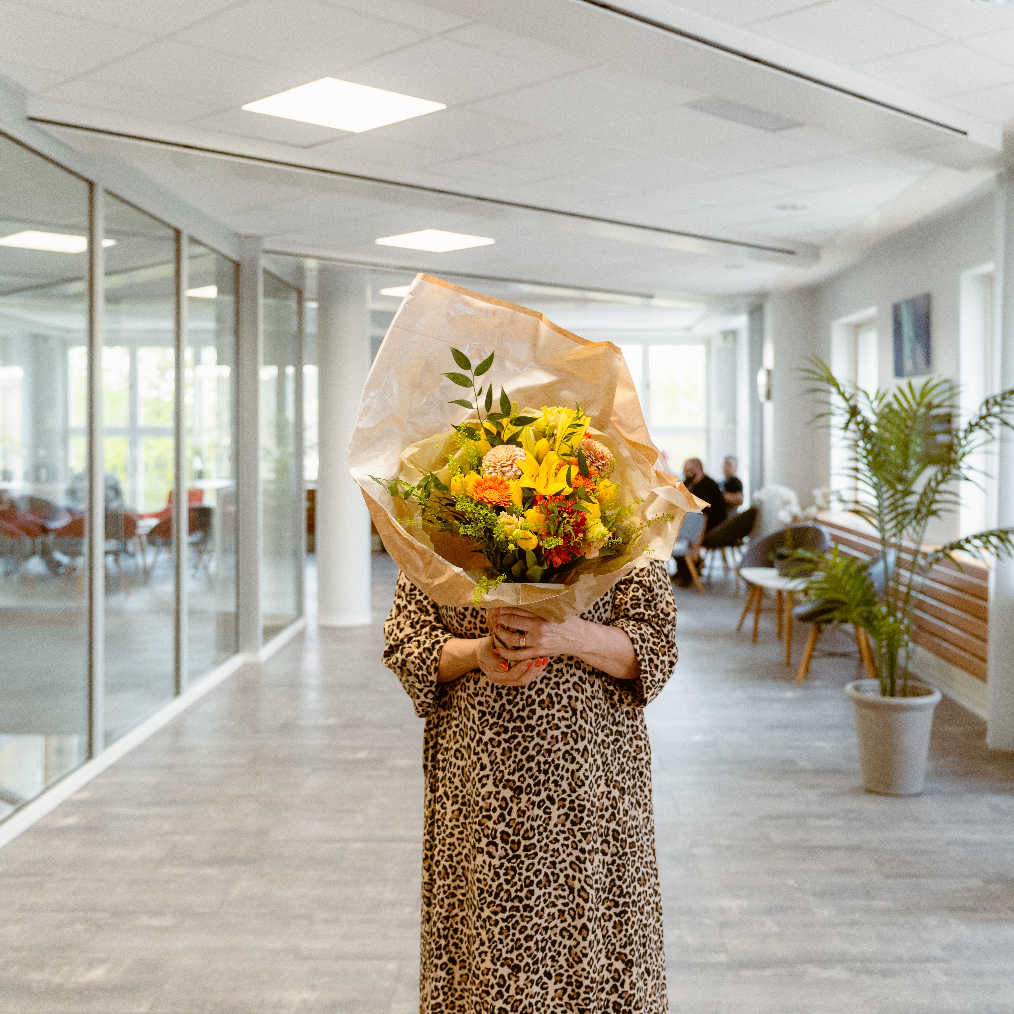 En person håller en stor bukett blommor framför sig