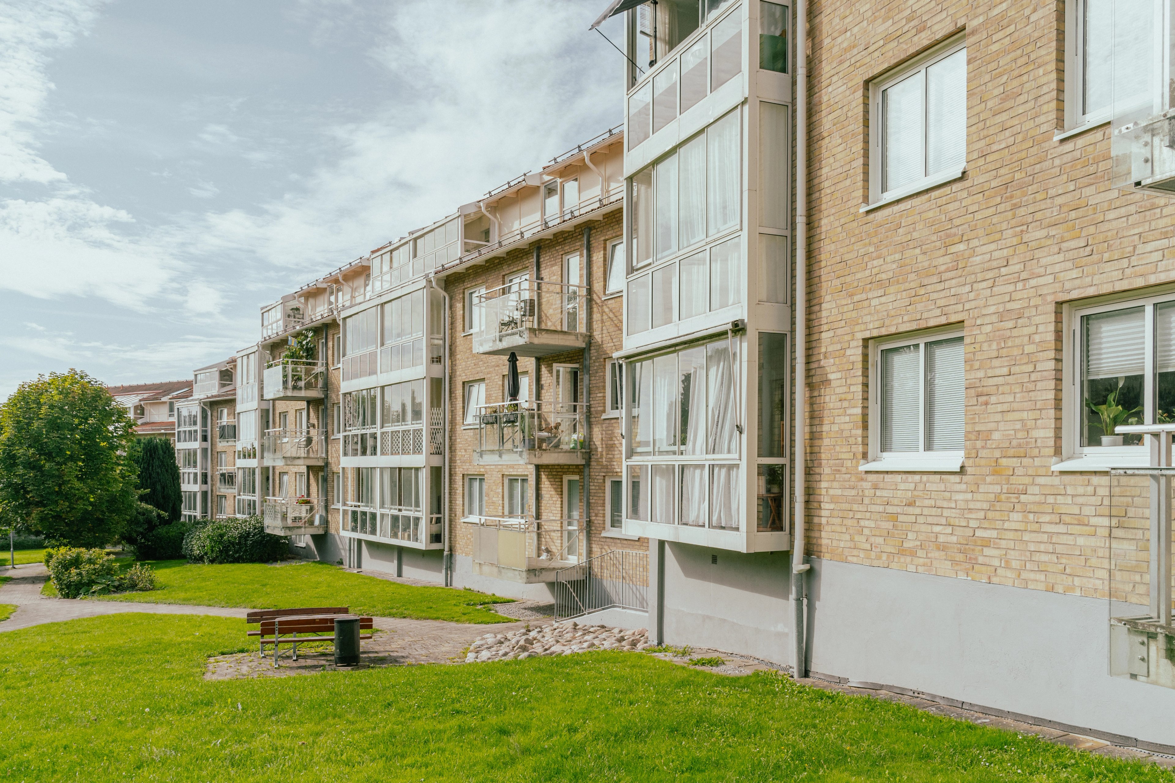 En lång huskropp med gräsmatta och bänkar framför