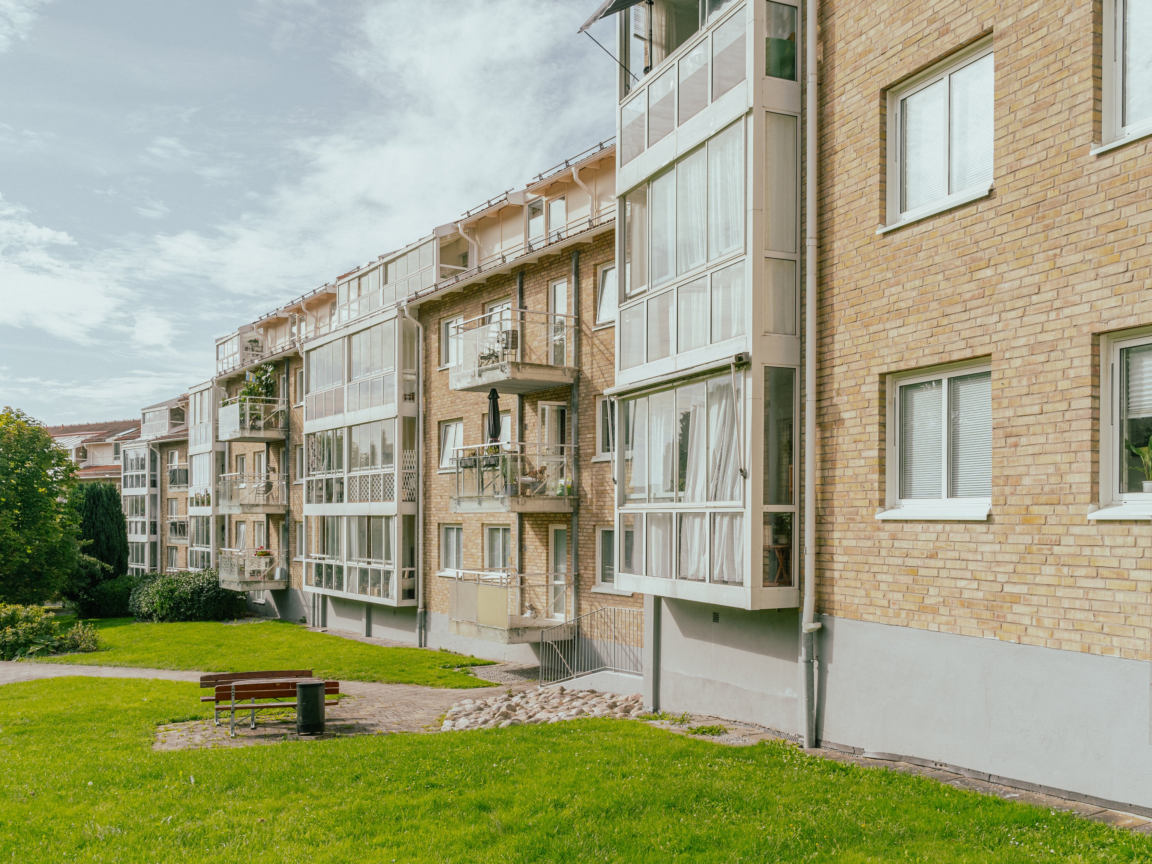 En lång huskropp med gräsmatta och bänkar framför