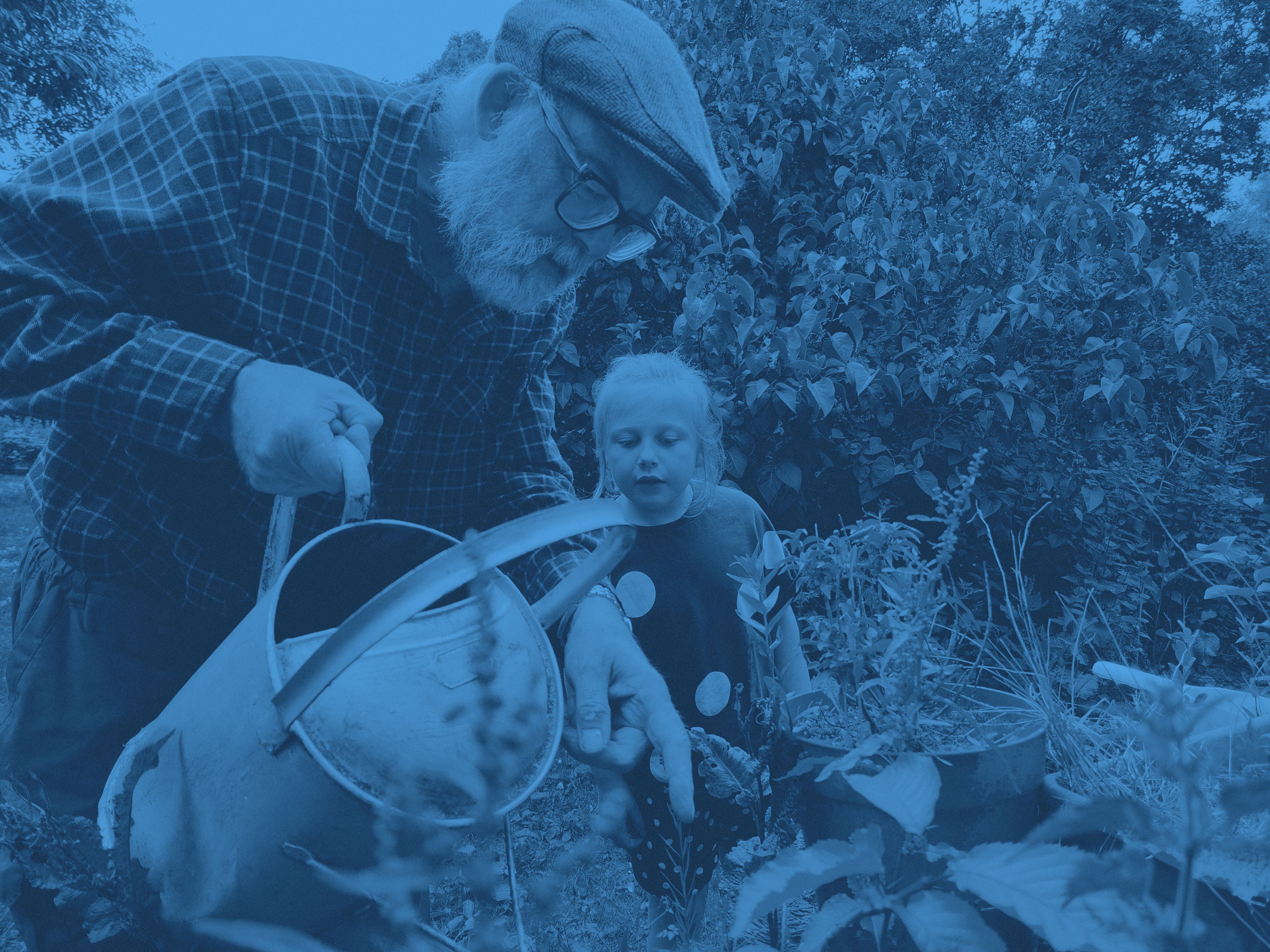 En man och barn vattnar i trädgården