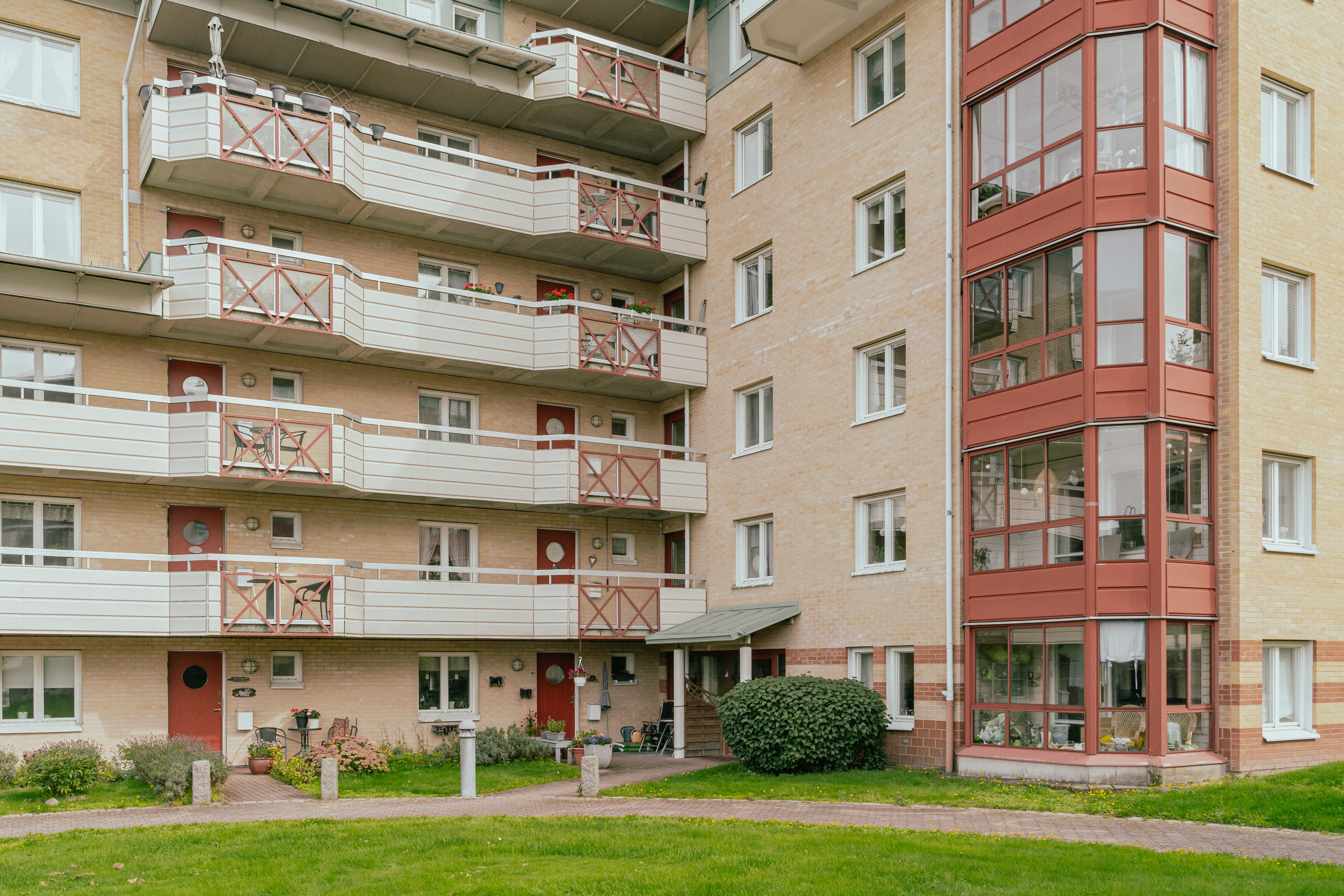 Åtta våningars husfasad med balkonger och uteplatser