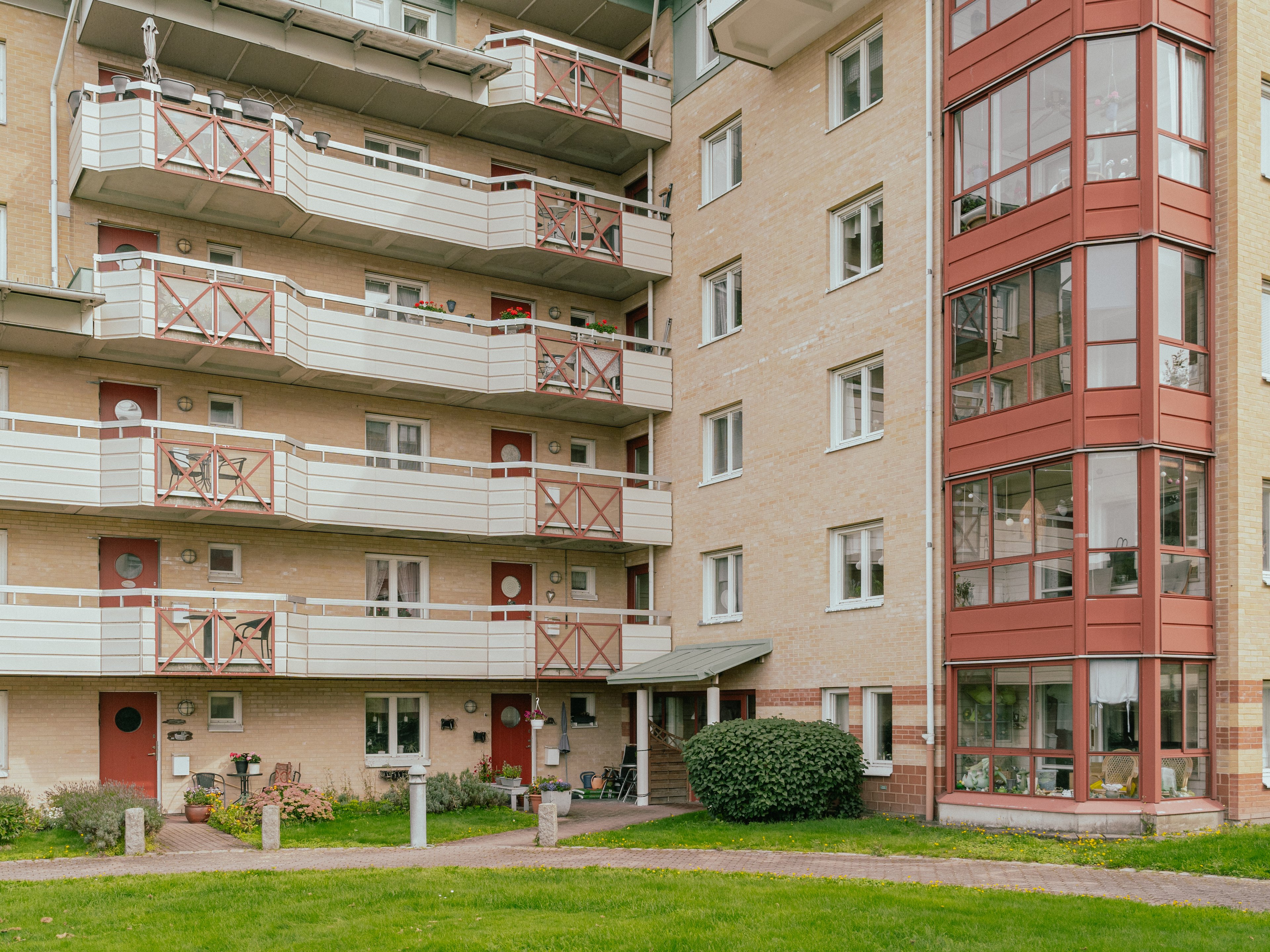 Åtta våningars husfasad med balkonger och uteplatser