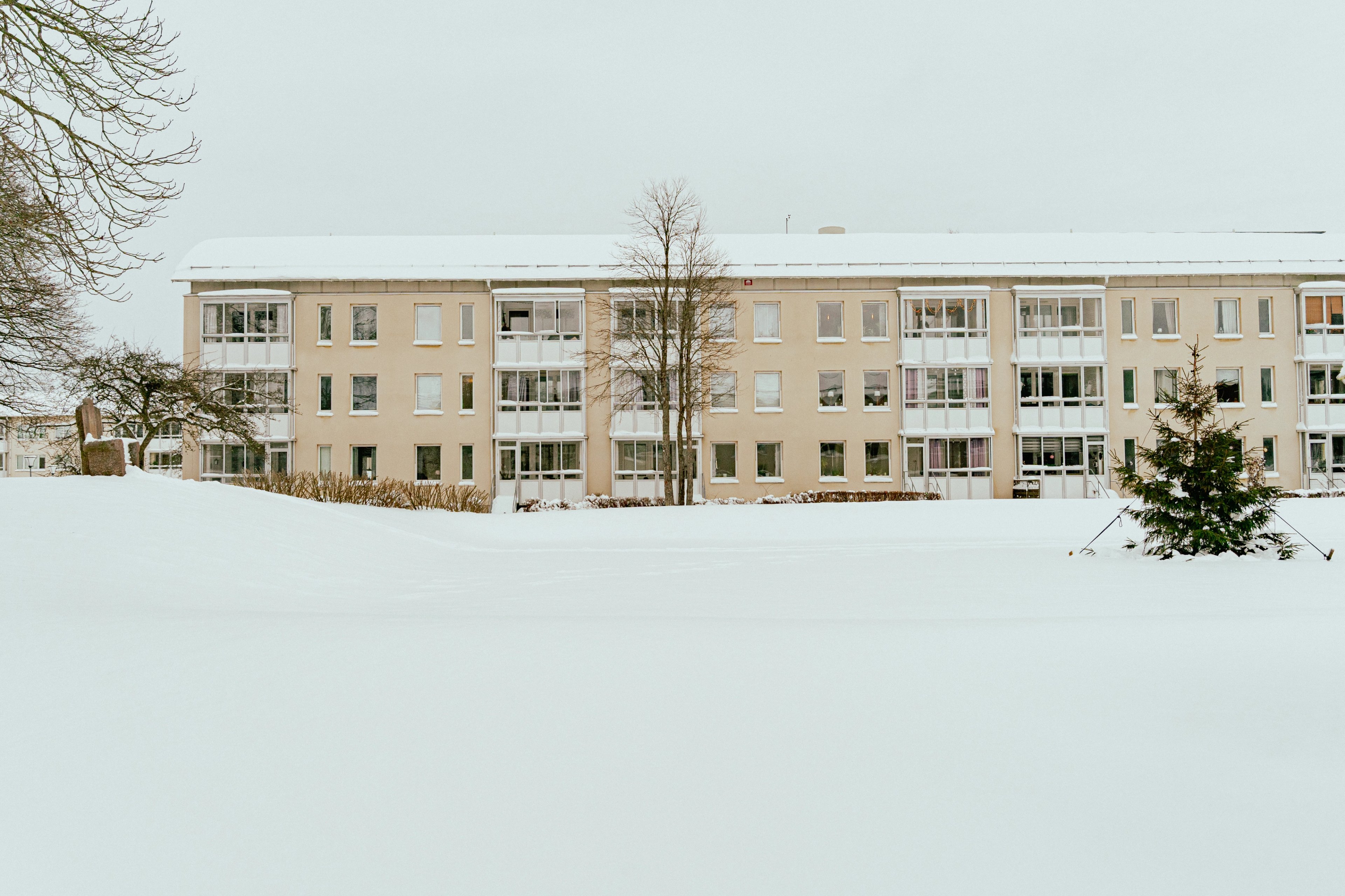 En husfasad på avstånd med snötäckt mark framför