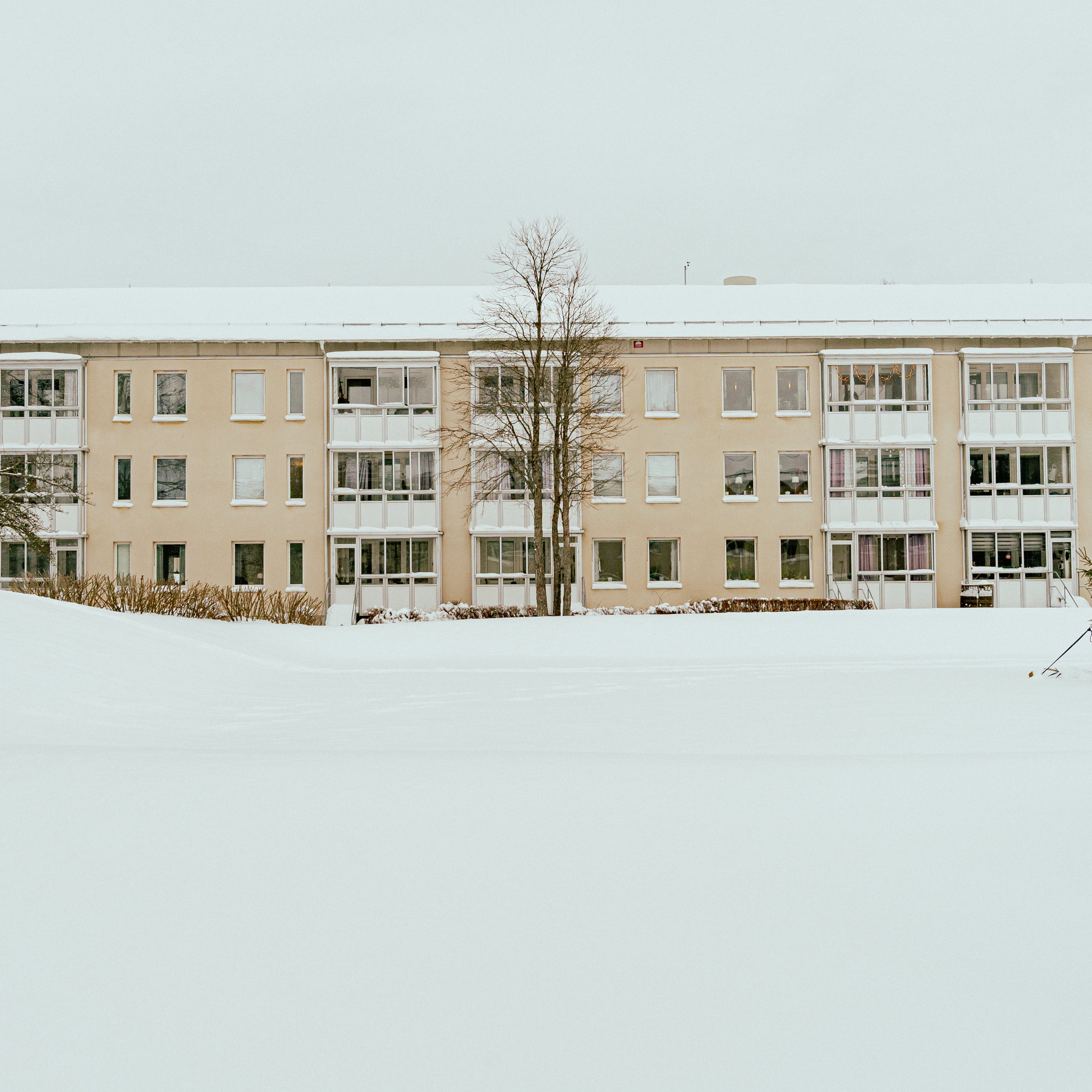 En husfasad på avstånd med snötäckt mark framför