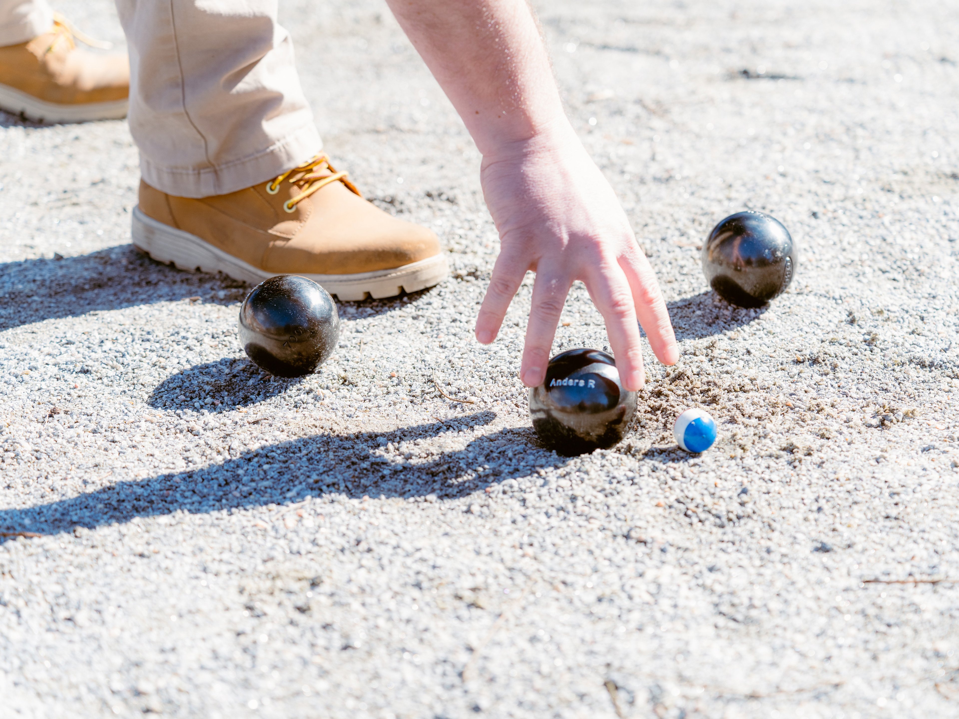 Närbild på en fot, en hand och tre boulklot