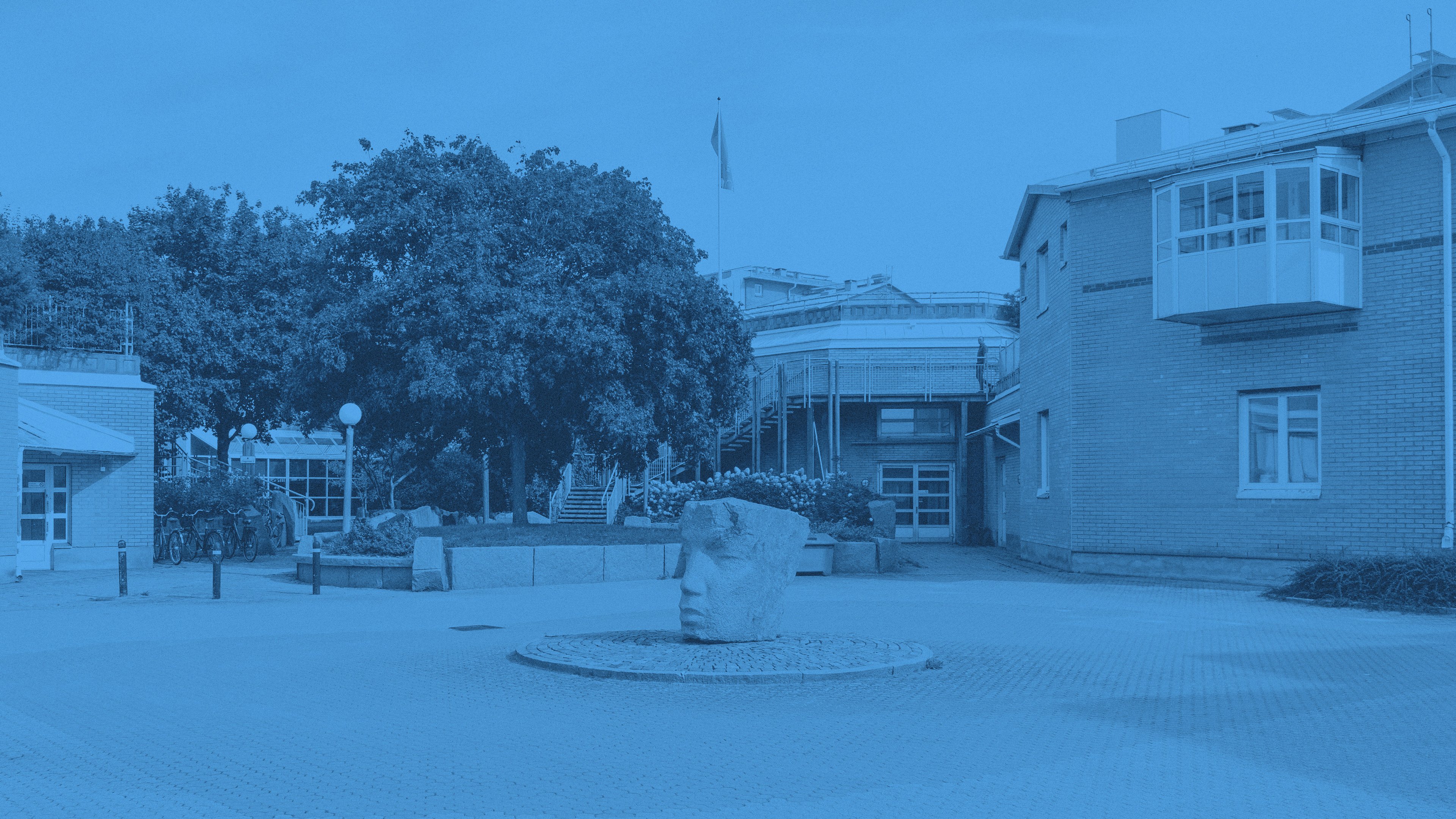 Ett konstverk i granit, i en rondell, framför hus och träd