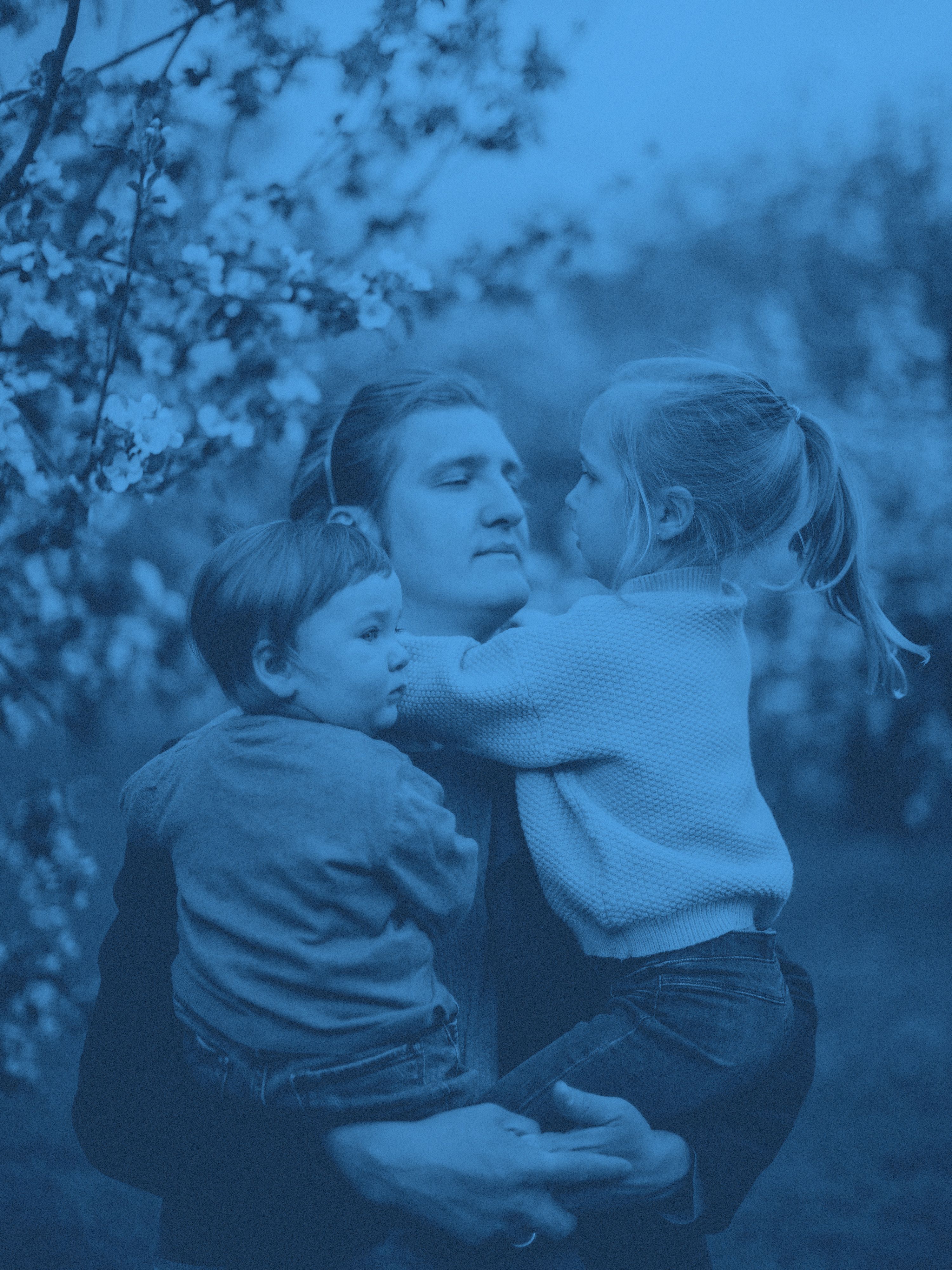 En pappa med två barn i famnen