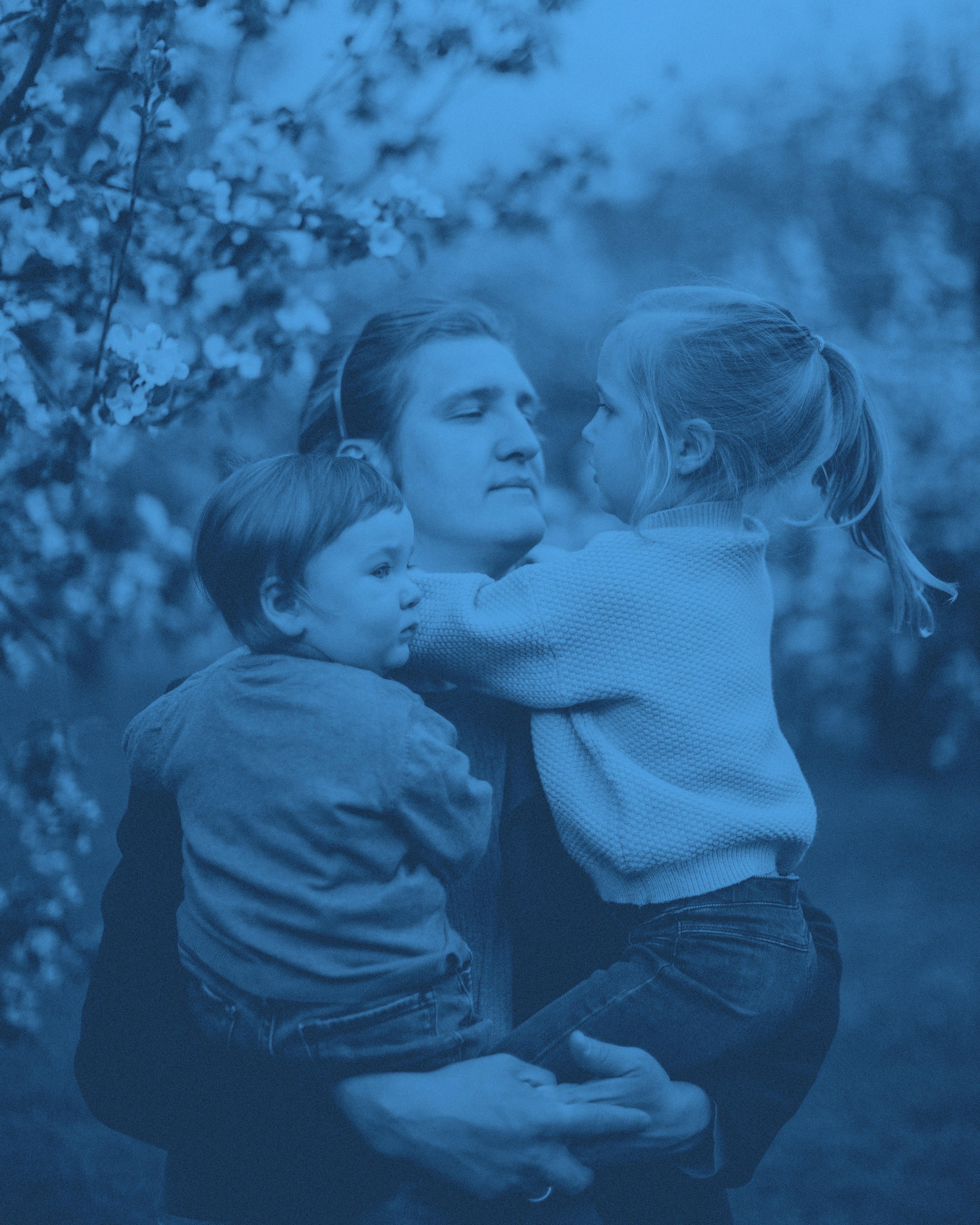 En pappa med två barn i famnen