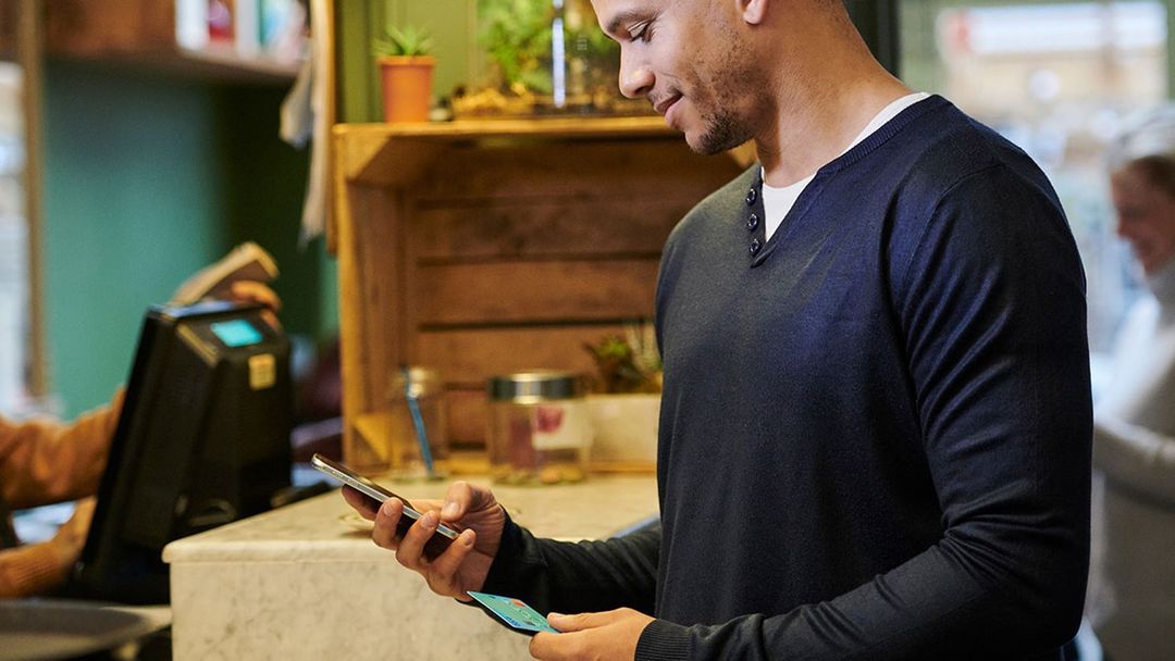 Close up of an adult male holding a smart phone and credit card, typing a message into a phone. 