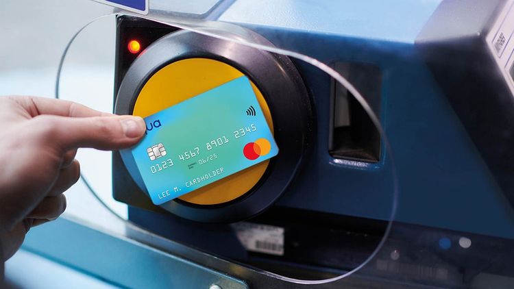 Close-up of human hand tapping an aqua credit card on bus tfl card reader.