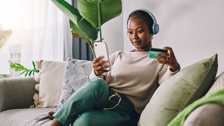 Adult woman in casual clothing relaxing indoors on her sofa wearing headphones.