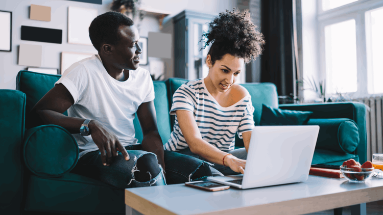 man and woman sitting on sofa with laptop