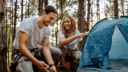 man and woman setting up a tent in the woods