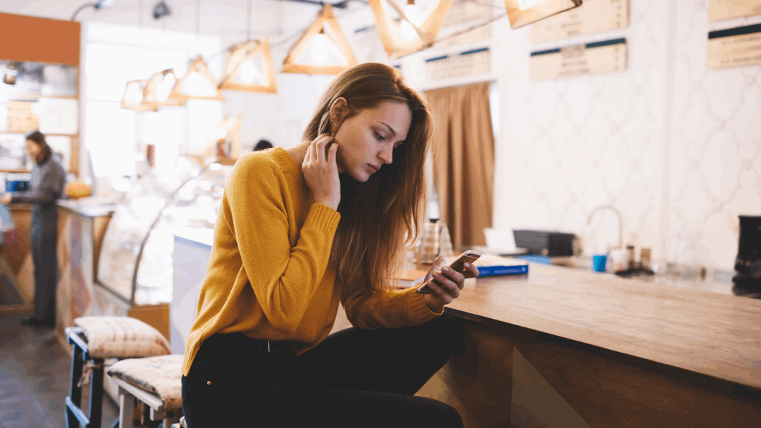 Girl sat in a cafe looking at her phone
