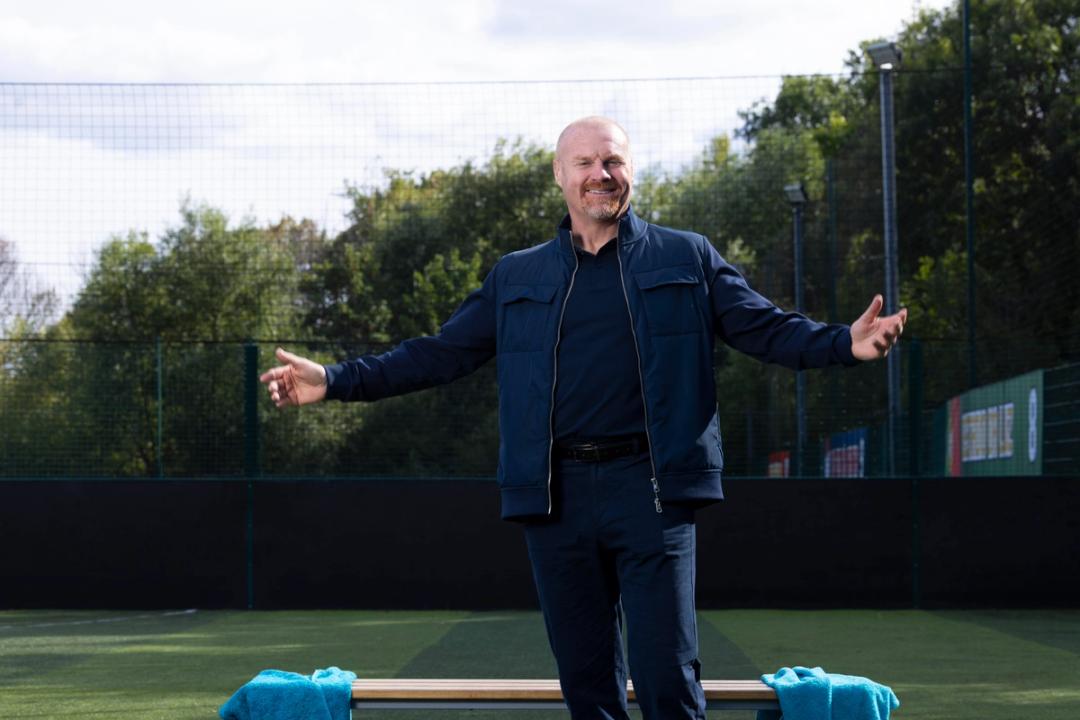 Football coach Sean Dyche standing on a pitch with open arms