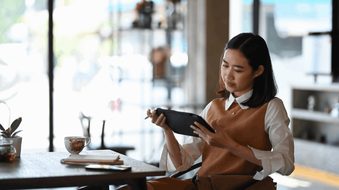 Woman sat at a table looking at an tablet