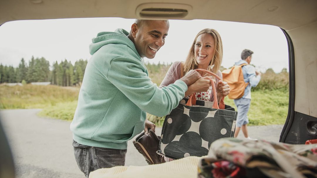 Couple loading bags into car boot