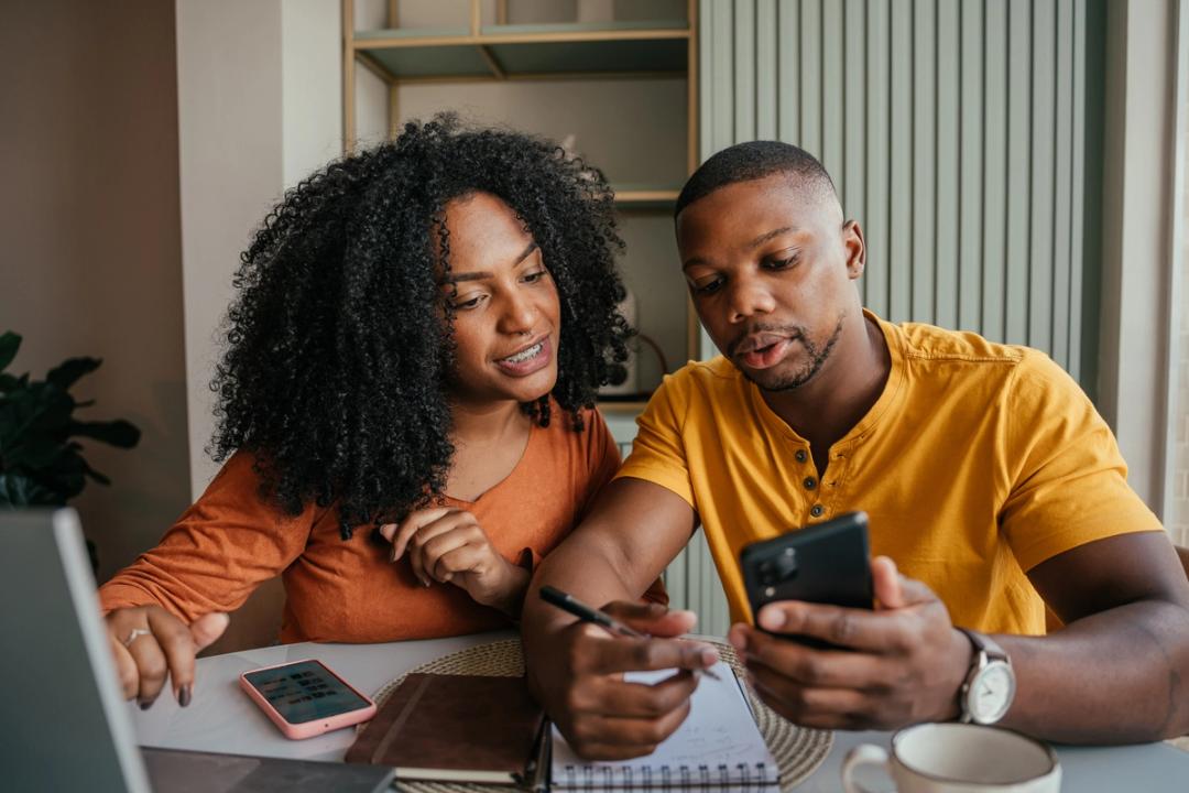 Couple looking at their phone and writing notes
