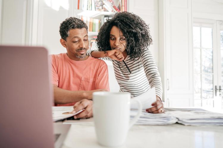 Couple looking at bills in front of a laptop