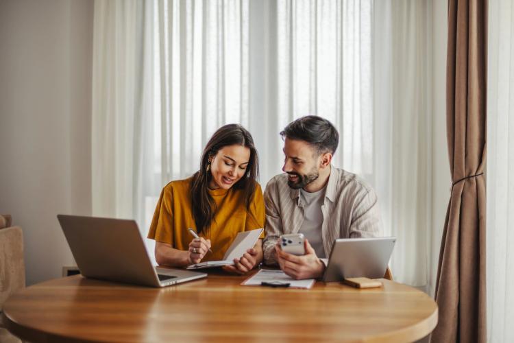 Couple sat at the table looking at laptop