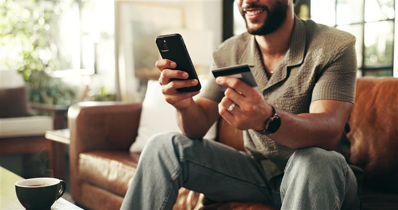 Man smiling at his phone and credit card