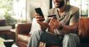 Man smiling at his phone and credit card