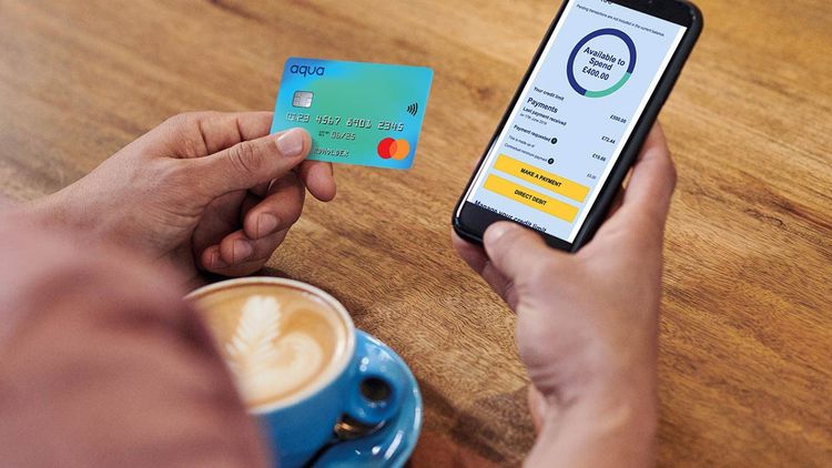 Close-up of adult man's hand holding mobile phone, coffee drink, and credit card.