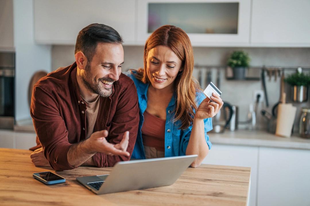 Man and woman looking at a laptop while woman holding a credit card