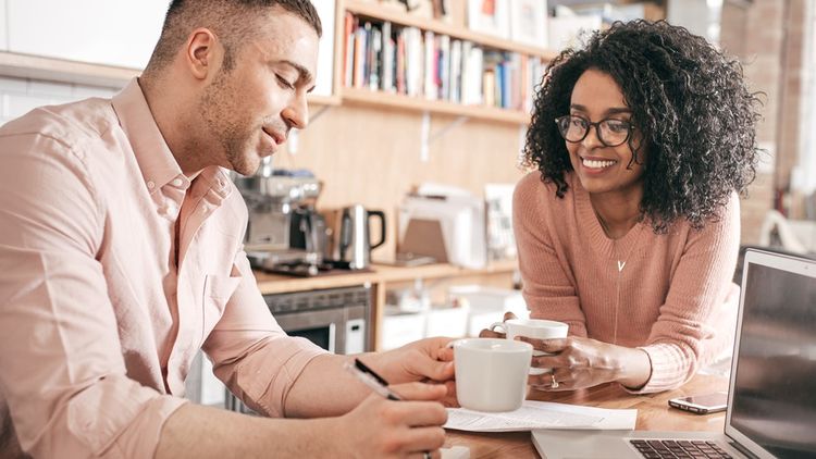 Man and woman sitting at at table, drinking coffee and reviewing paperwork.