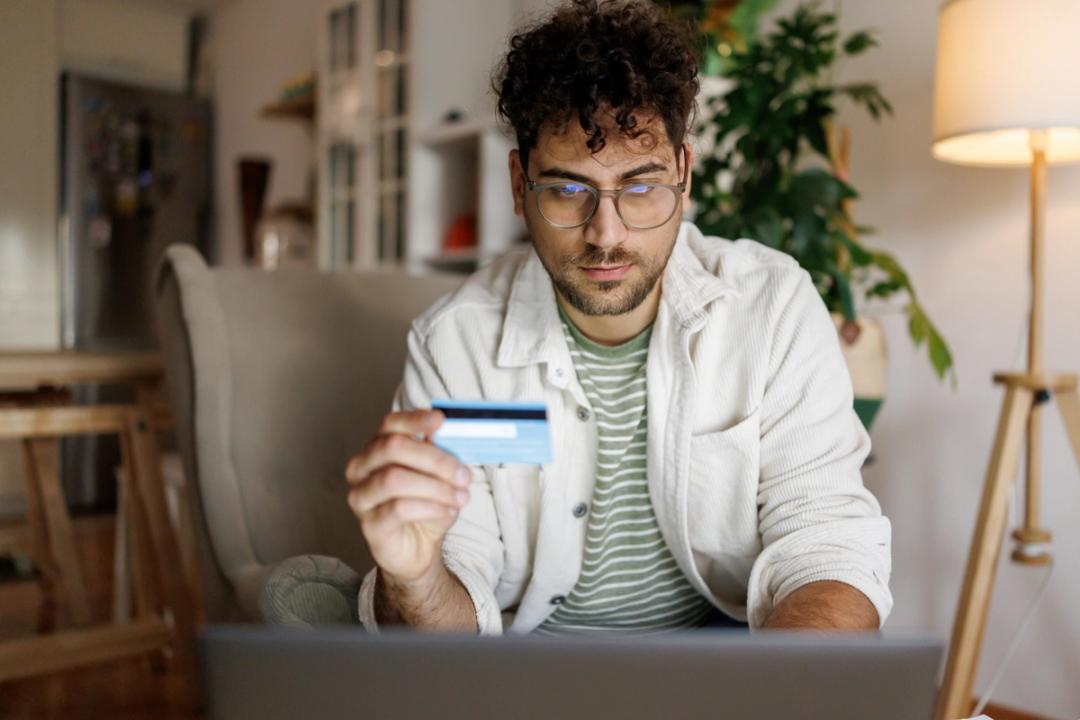 Man holding credit card in front of laptop