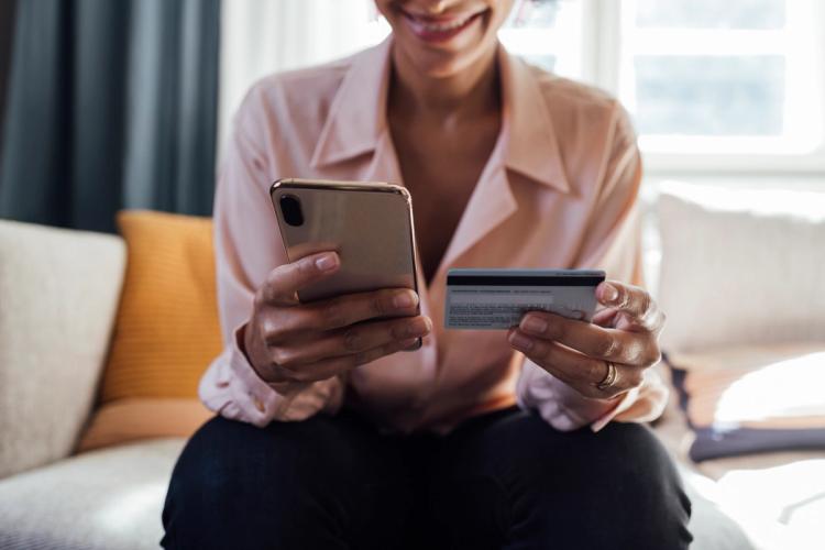 Woman smiling holding her phone and credit card