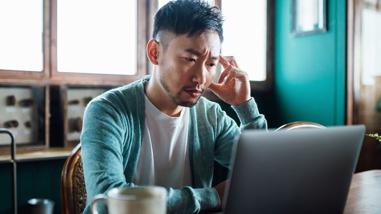 Young adult male working with laptop indoors.