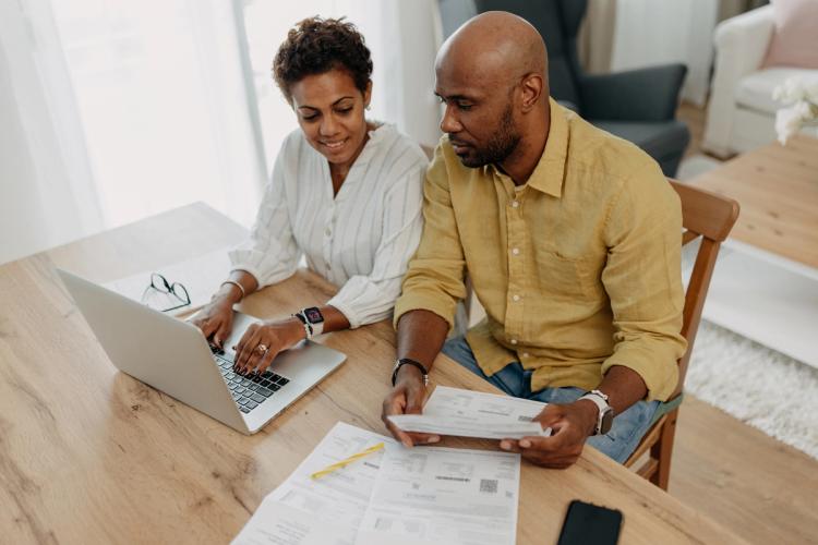 Couple looking at their laptop with bills on the table