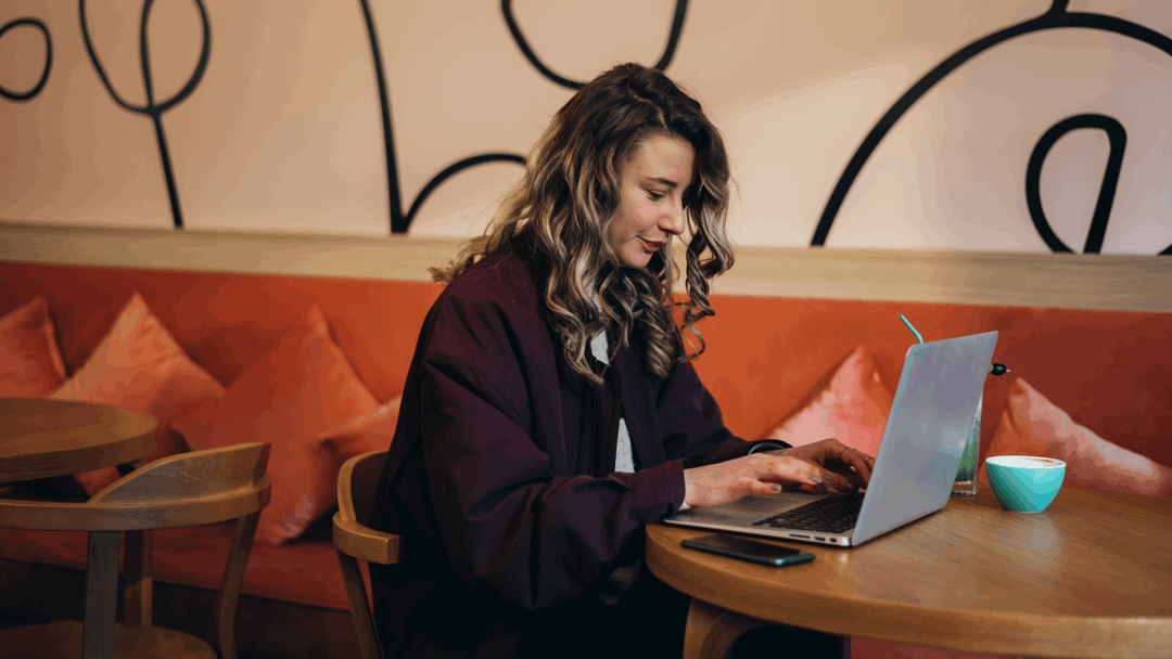 Young girl sitting in a cafe looking at her laptop